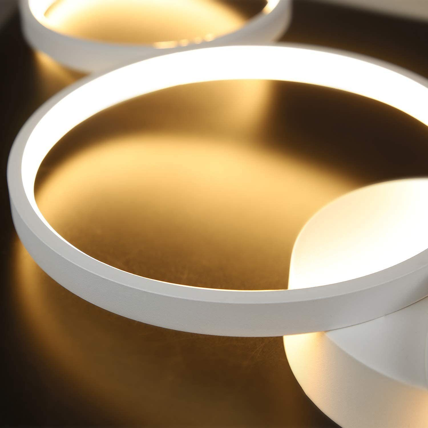 Zbliżenie dwóch okrągłych białych lamp sufitowych o jasnym blasku i złotym wnętrzu.
