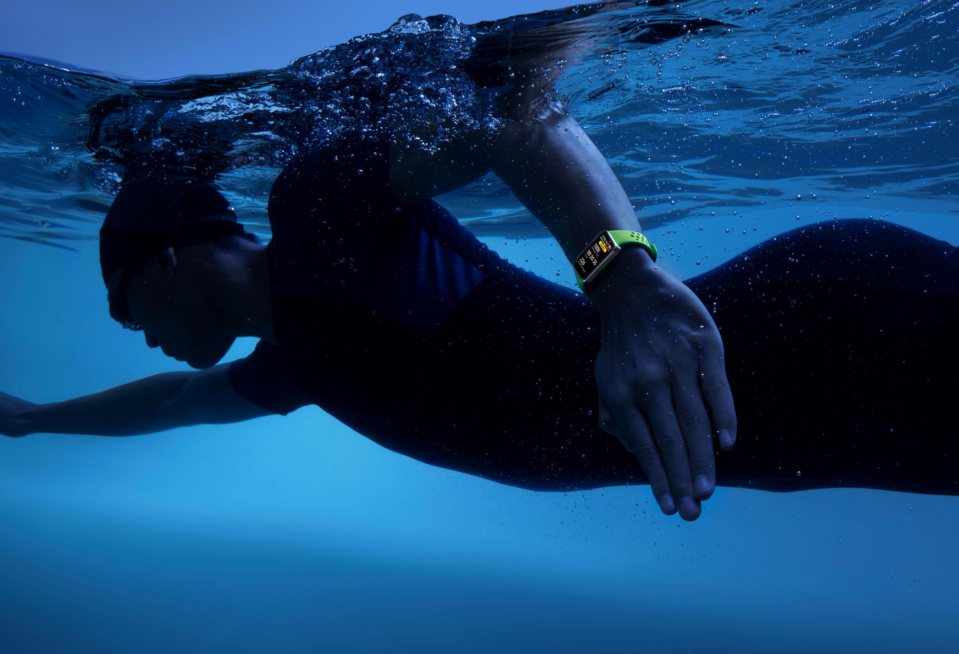 Nadador en agua, con gorro y reloj inteligente, vista submarina.