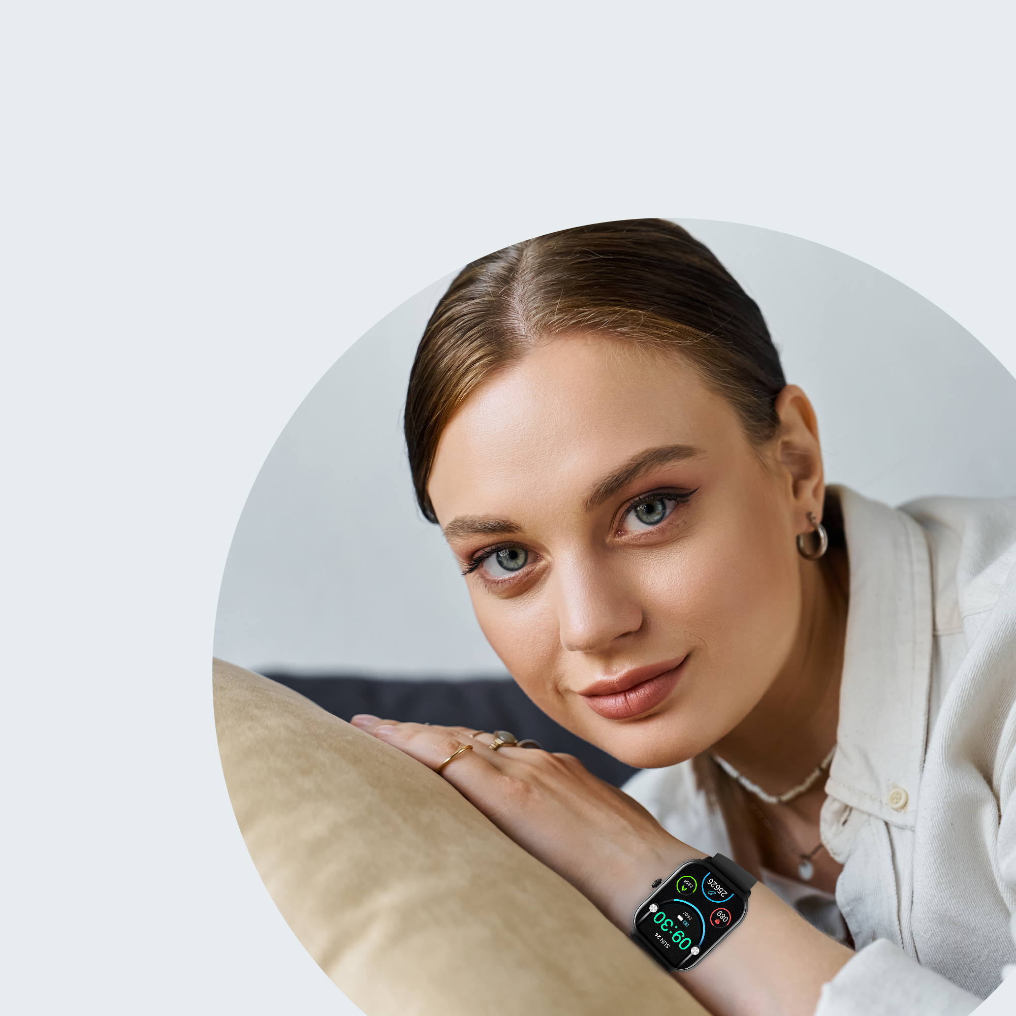 Een vrouw met een smartwatch om haar pols, ze leunt op een kussen. De achtergrond is wazig.