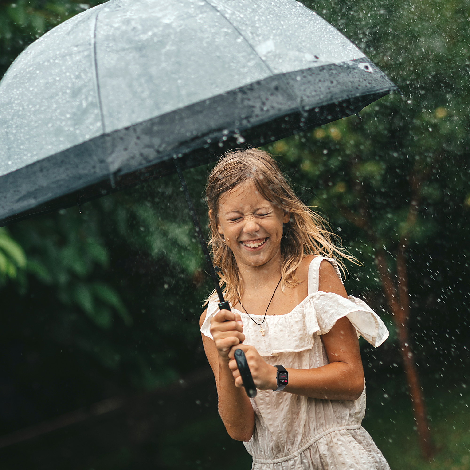 Une fille souriante, tenant un parapluie sous la pluie.