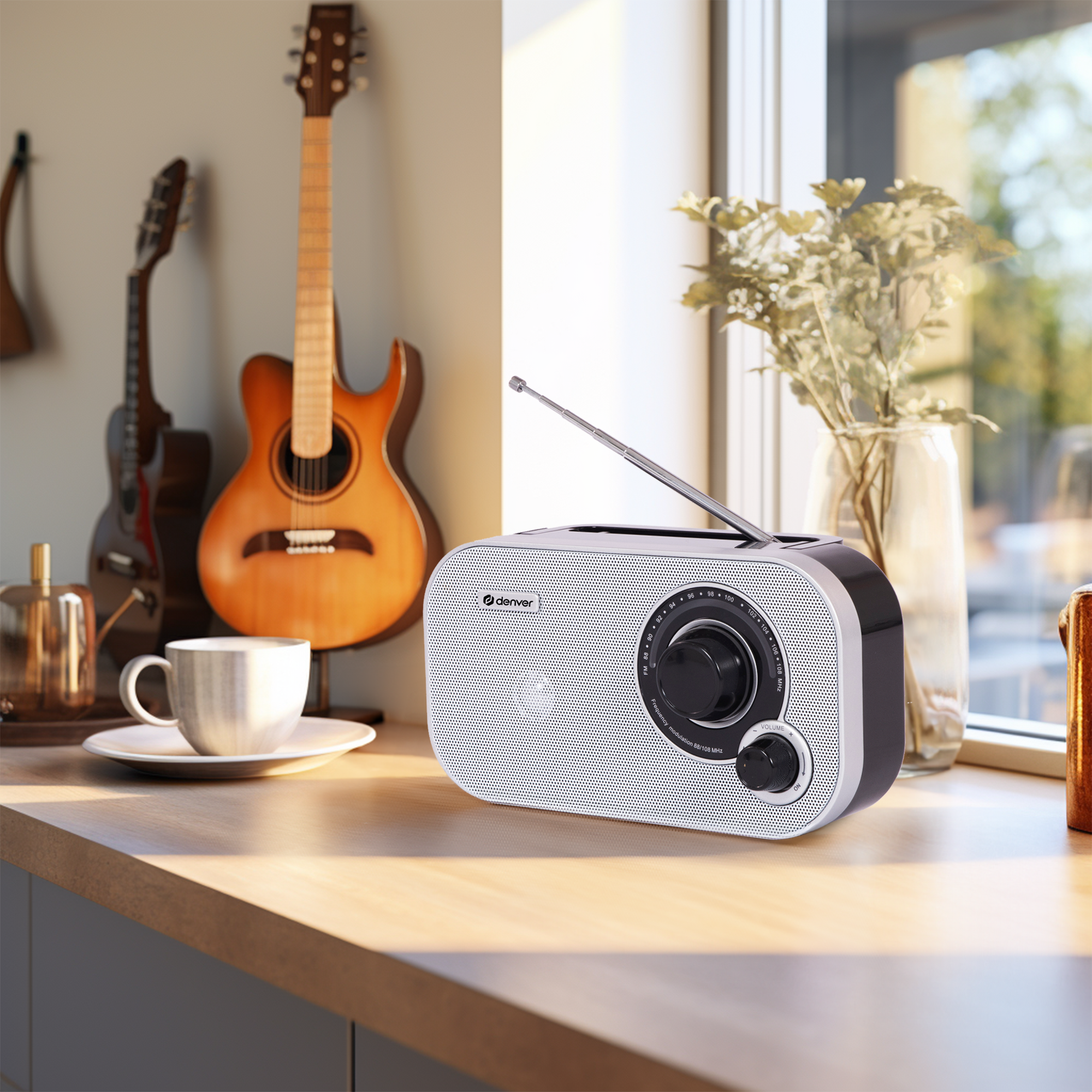 Radio na drewnianej powierzchni. Gitary i okno z tyłu. Kubek po lewej.