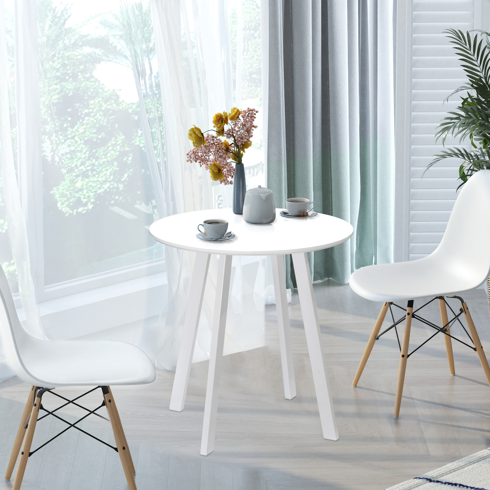 Weißer Tisch mit Blumen und zwei Stühlen an einem Fenster mit weißen Vorhängen.