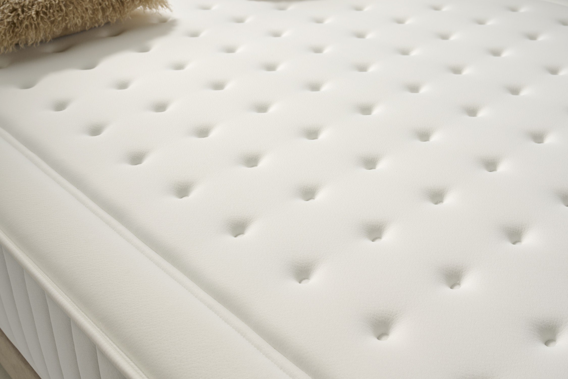 Un primer plano de un colchón blanco con mechones de botones.