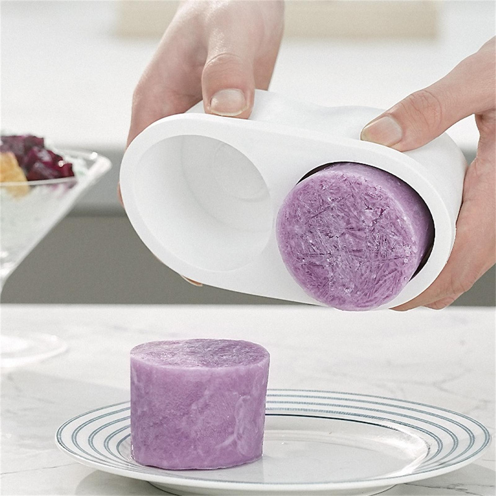Hände verwenden eine Maschine, um einen lila Eisblock zu einem Zylinder zu formen.