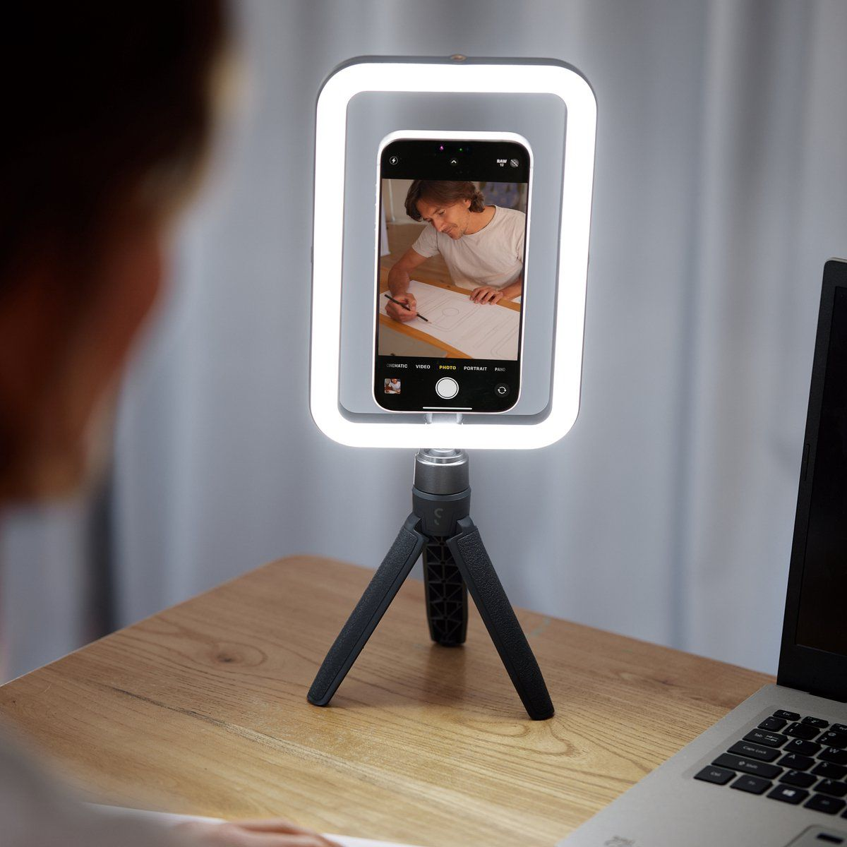Tripod üzerinde halka ışıklı bir telefon. Bir kişi telefon ekranında kağıda çizim yapıyor.