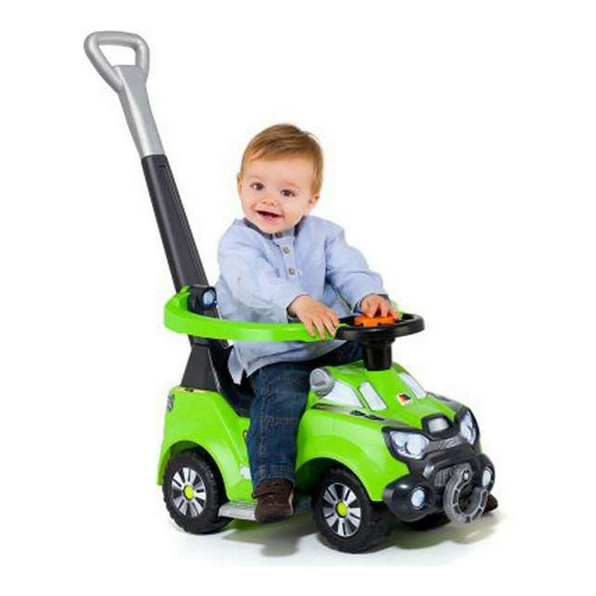 Un bambino seduto su un'auto giocattolo verde con un manico. Il bambino sorride.