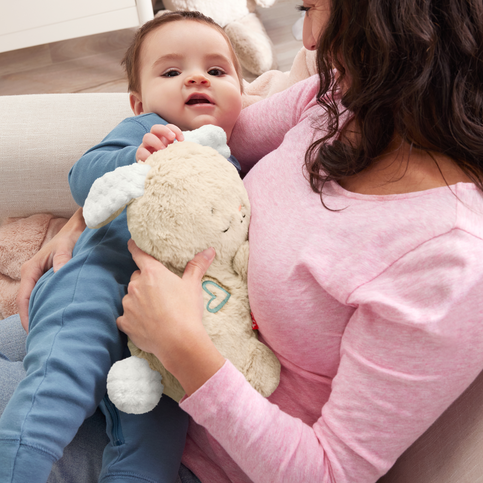 Niemowlę w niebieskiej piżamie z pluszakiem trzymanym przez kobietę.