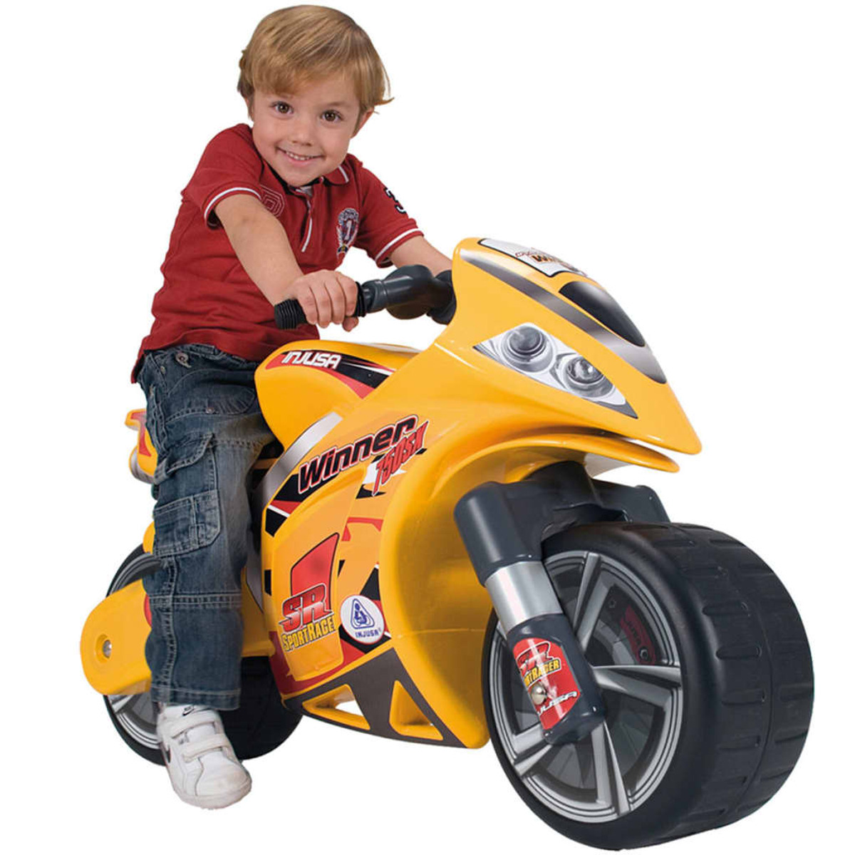 Un bambino che guida una moto giocattolo gialla. Il bambino indossa una maglietta rossa e jeans.