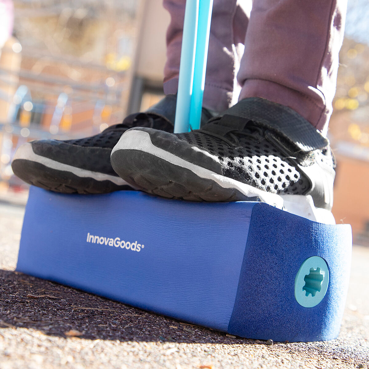 Niño en zancos de equilibrio azules. Los zancos tienen la marca InnovaGoods y están en un parque infantil.