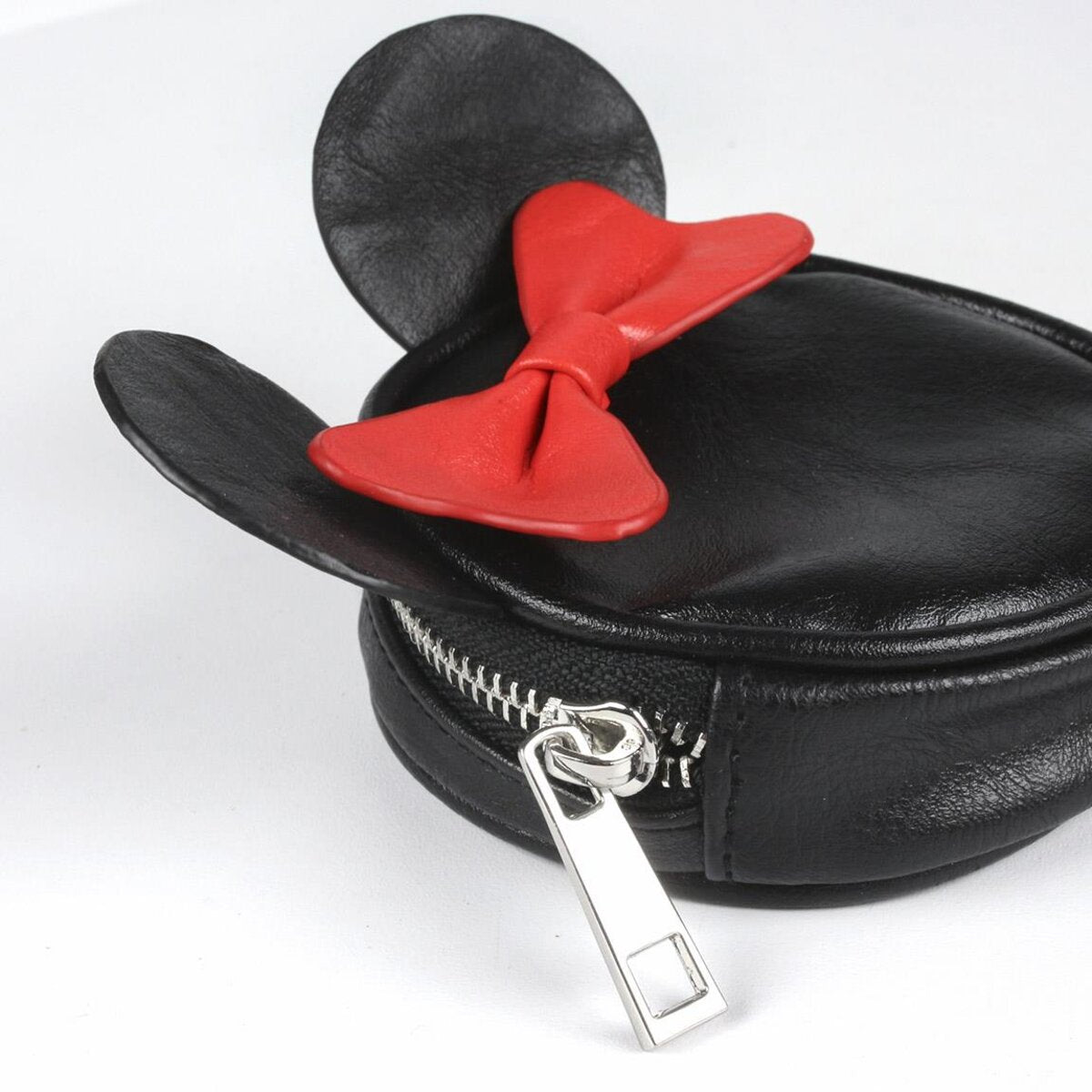 Un bolso negro con forma de Minnie Mouse con un lazo rojo y una cremallera plateada.