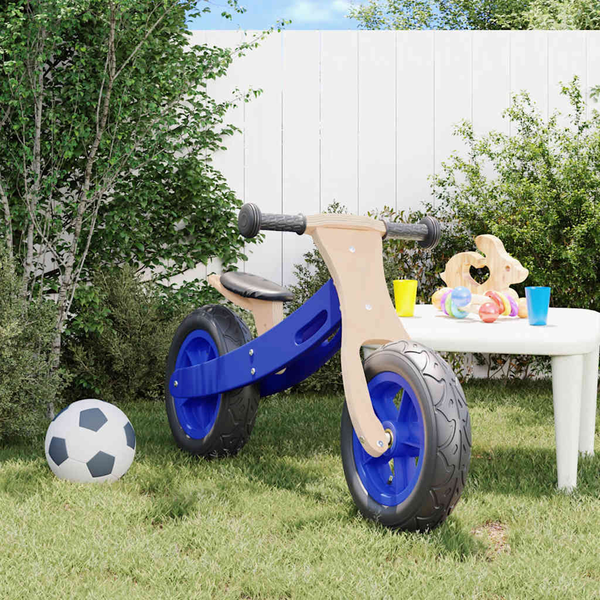 Blaues und hölzernes Laufrad mit Spielzeug auf einem Tisch, auf einer Wiese.