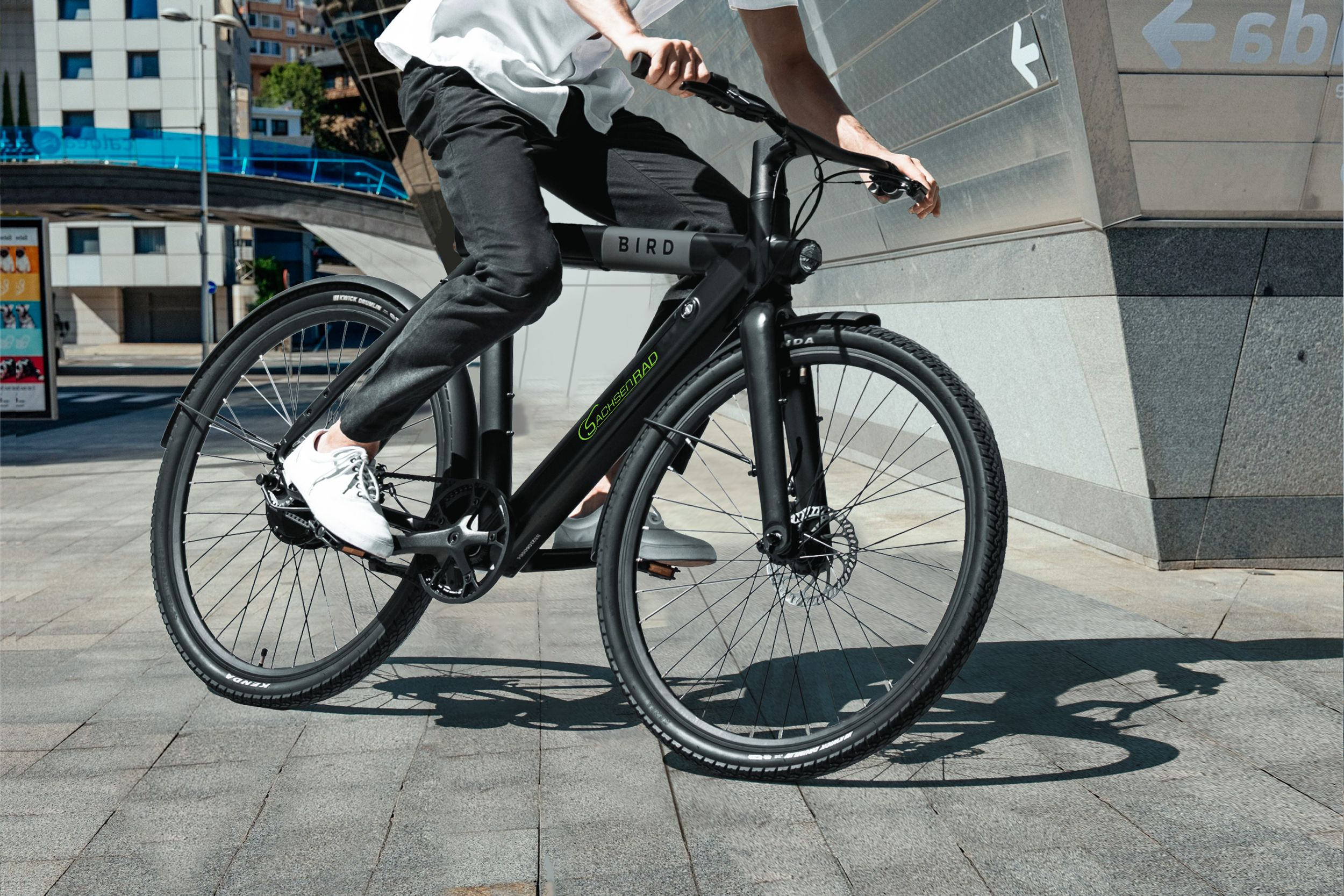 Eine Person fährt mit einem schwarzen Bird-Elektrofahrrad auf einer Stadtstraße.