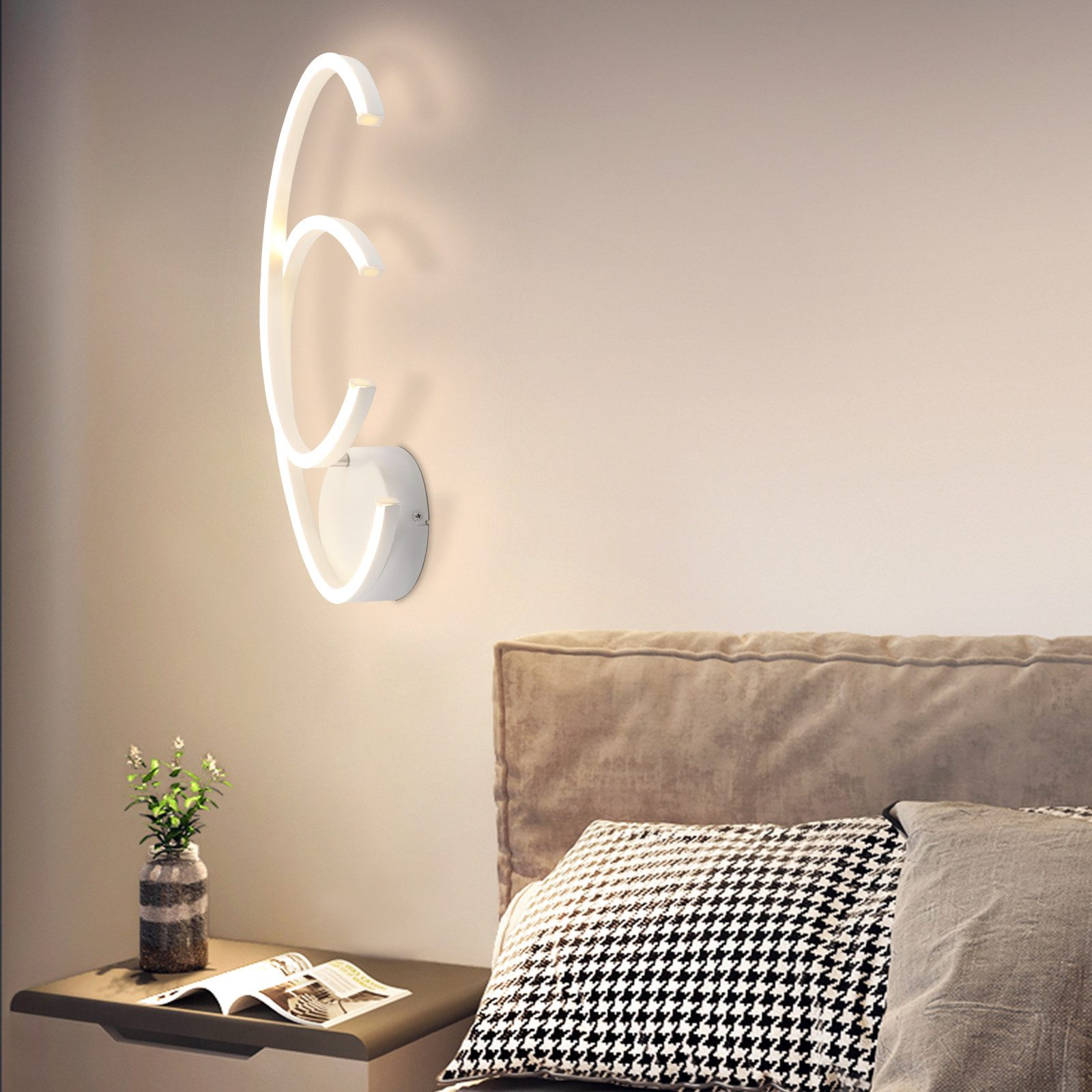 Lampada da parete con design curvo accanto a un letto e comodino.