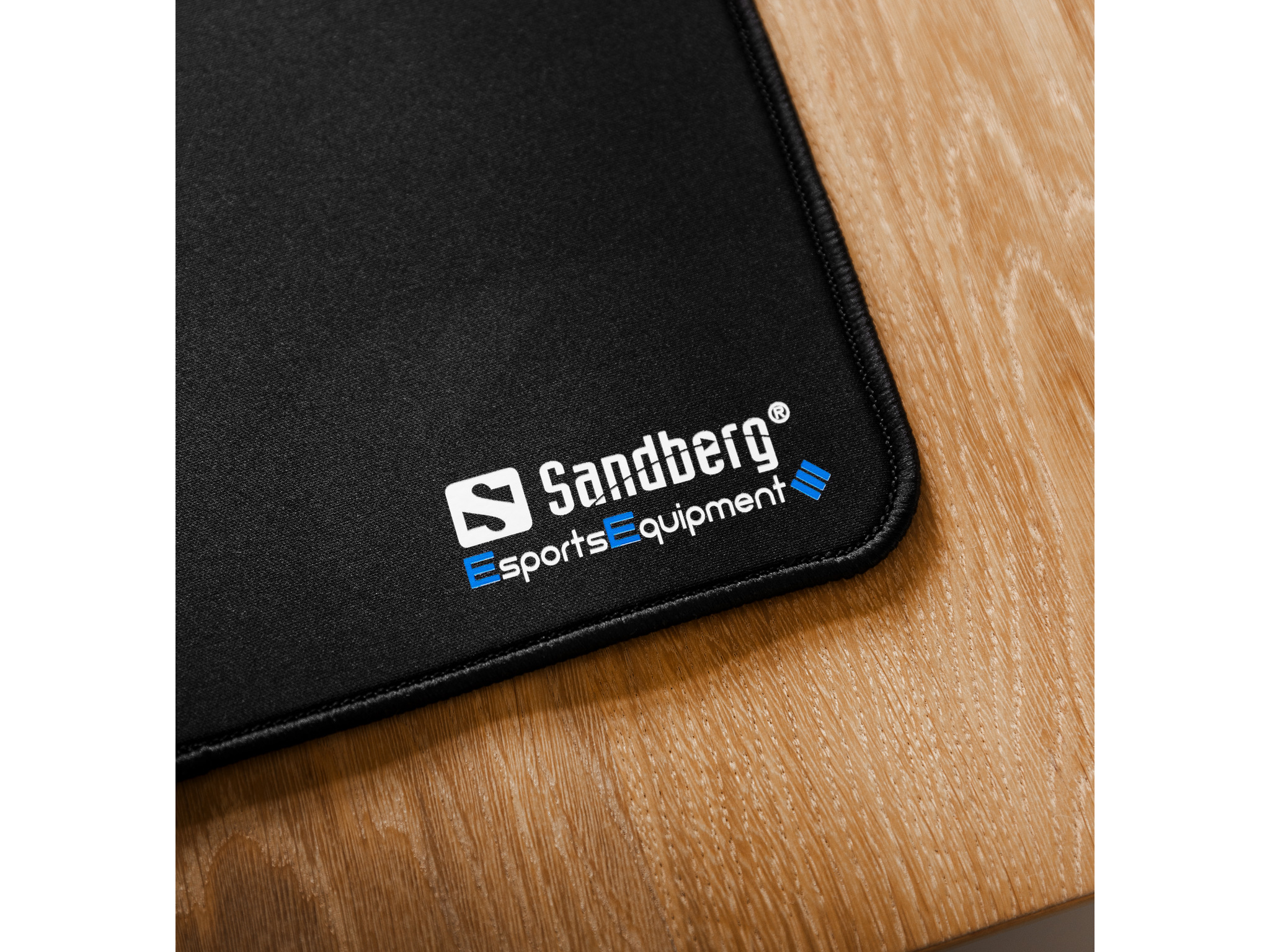 Czarna podkładka pod mysz z logo Sandberg Esports Equipment na drewnianej powierzchni.