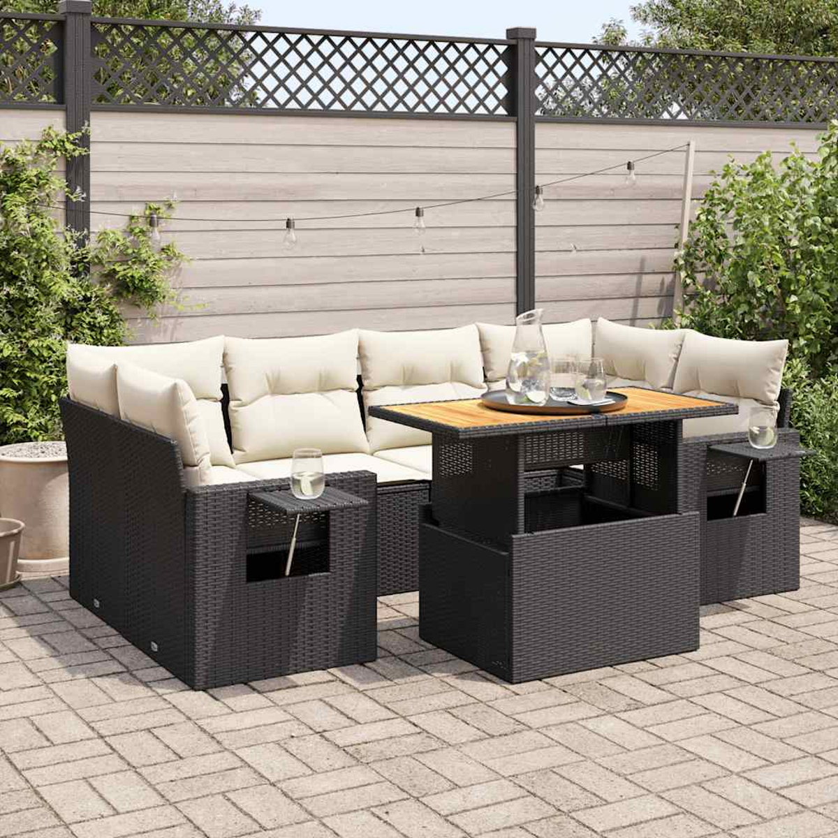 Un divano da esterno in rattan scuro con cuscini beige e un tavolo con bicchieri e una brocca.