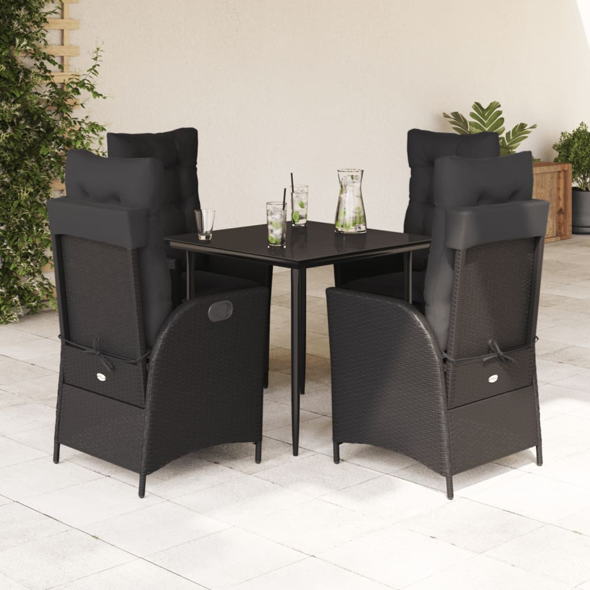 Schwarzes Ess-Set für den Außenbereich mit 4 Stühlen und Tisch. Getränke auf dem Tisch. Weiße Terrasse, Pflanzen im Hintergrund.