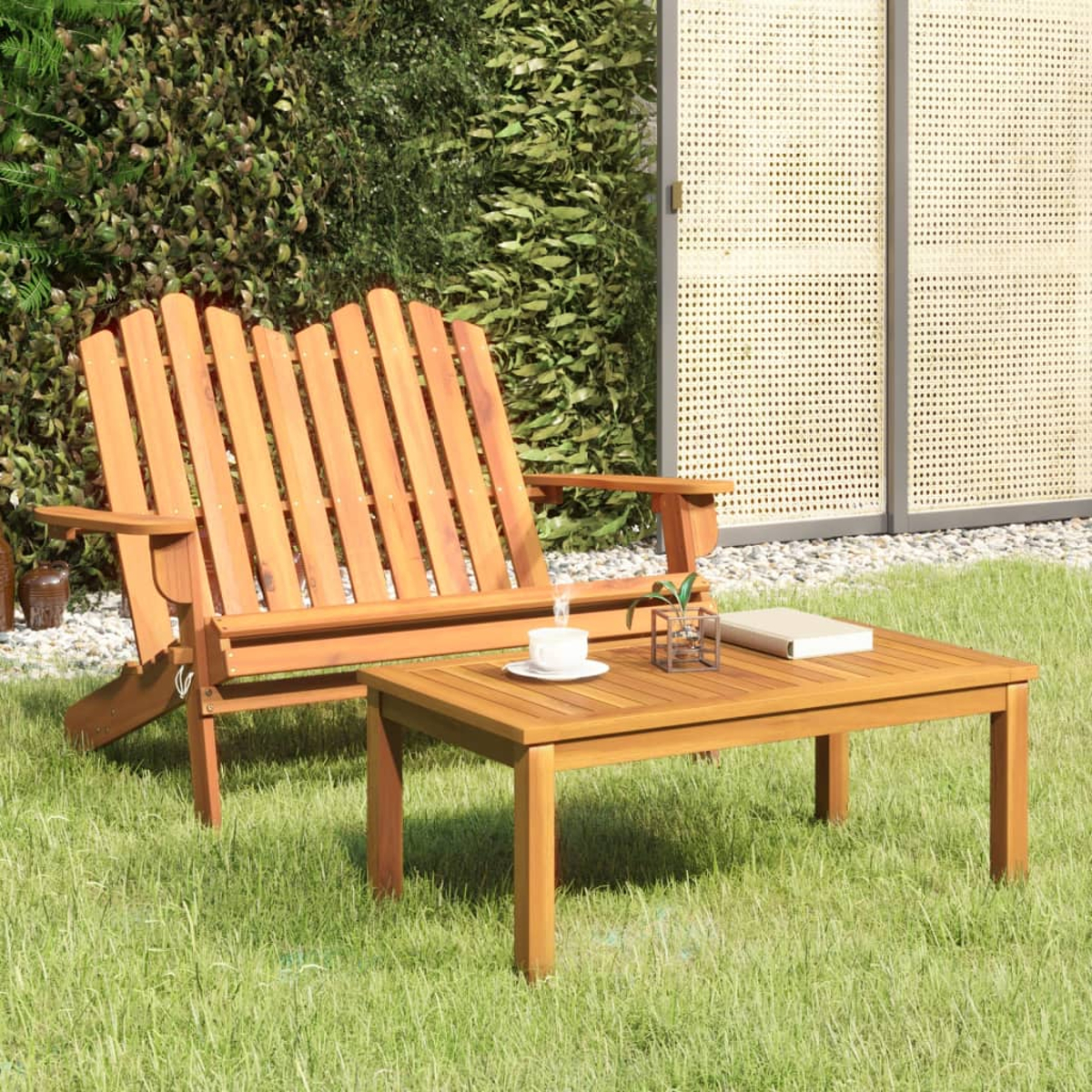 Holz-Outdoorsitzgruppe mit Bank und kleinem Tisch, auf Gras mit Pflanzen im Hintergrund.