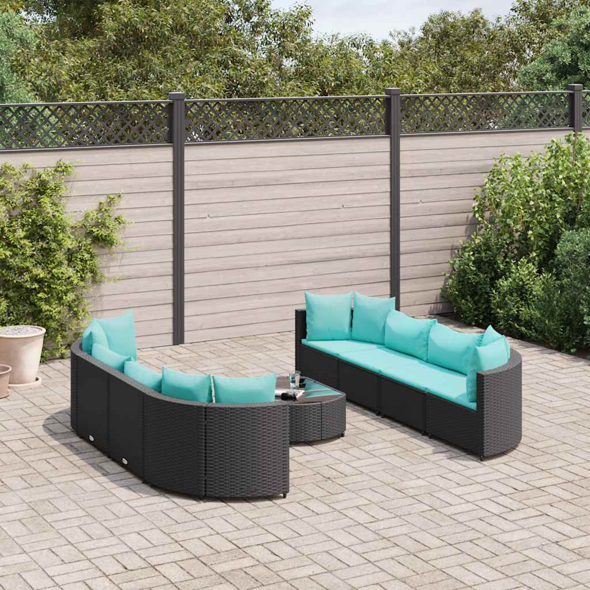 Arredamento per patio esterno con mobili in rattan nero, cuscini turchesi e un tavolino in vetro.