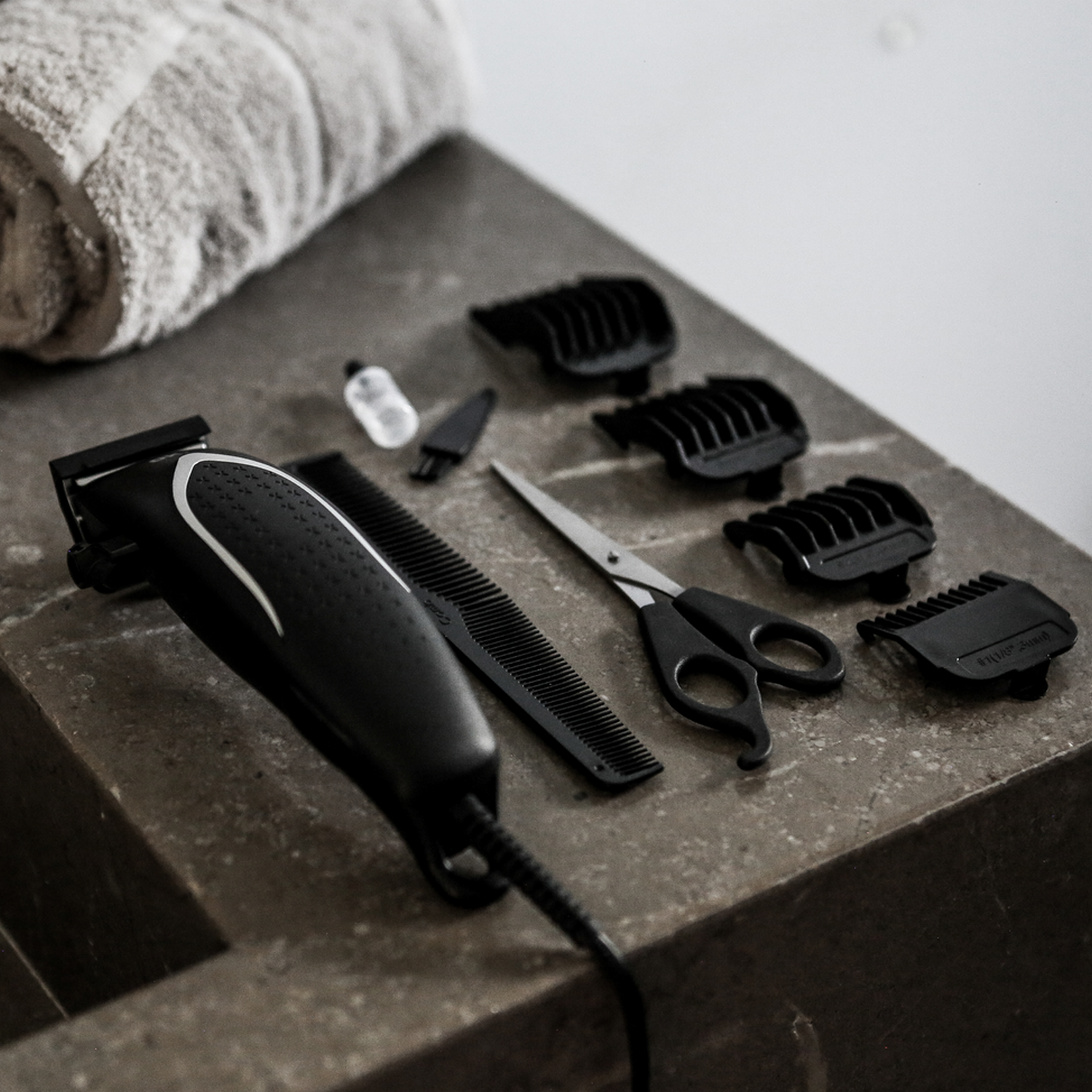 Ein Pflege-Set mit Haarschneidemaschine, Kämmen, Schere und Zubehör auf einer Oberfläche.
