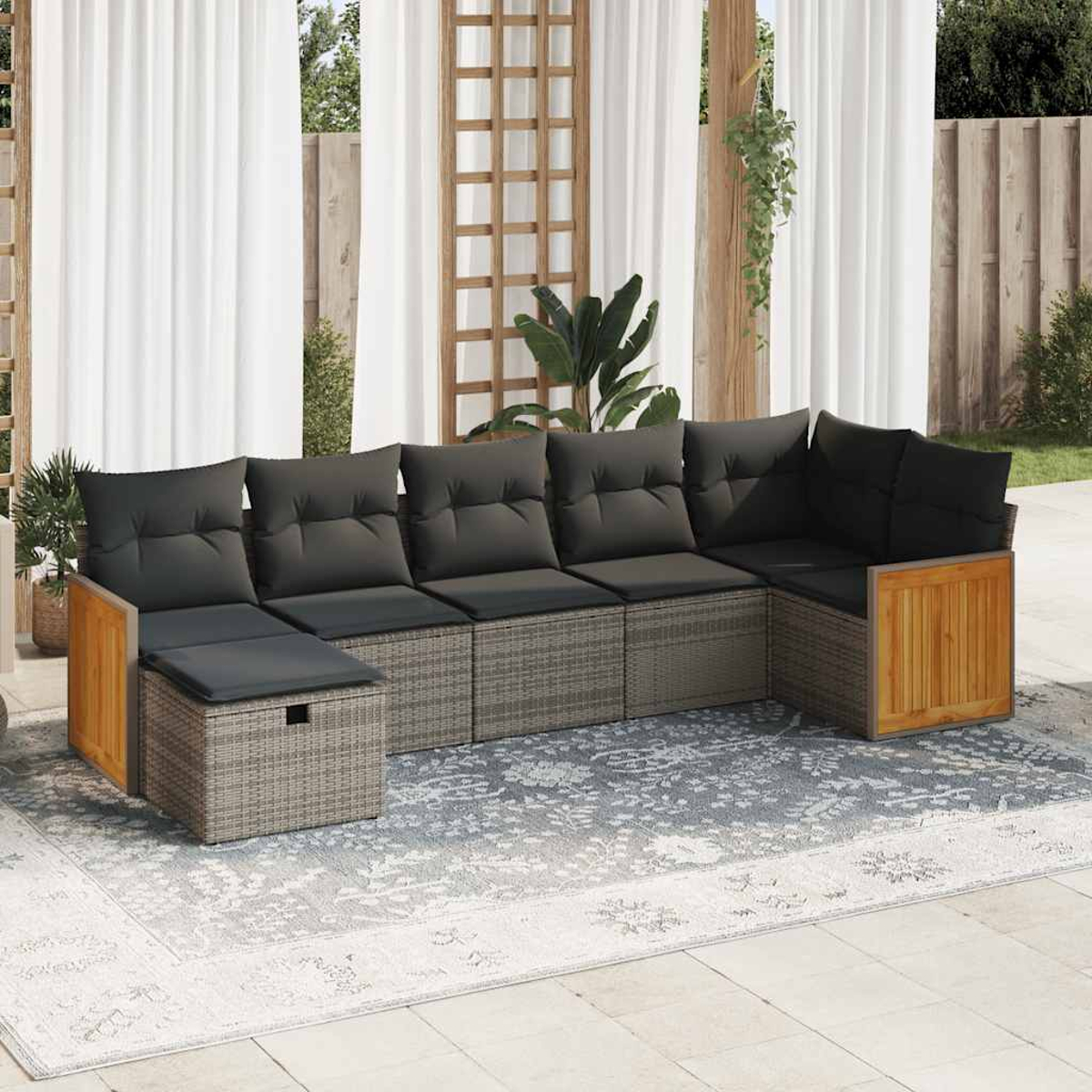 Ein graues Rattan-Ecksofa mit schwarzen Kissen und Holzakzenten steht auf einem grauen Teppich.
