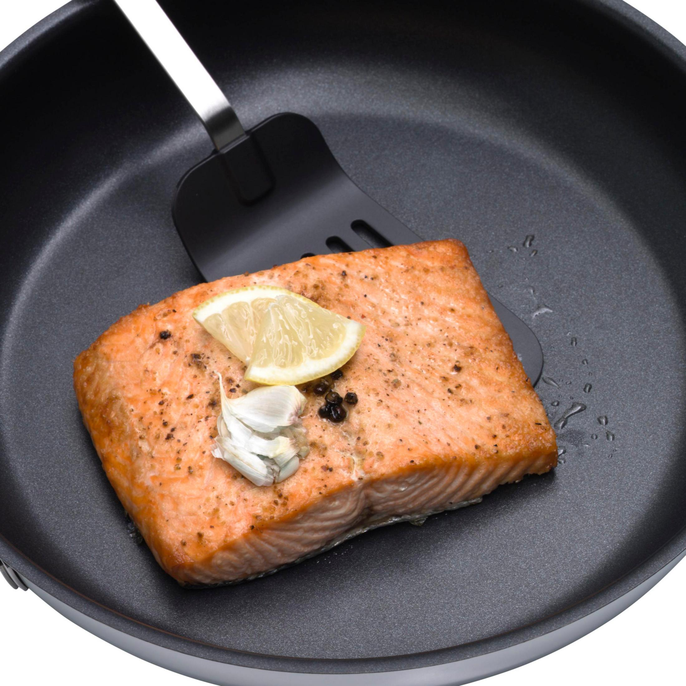 Gotowany filet z łososia na patelni z cytryną i czosnkiem. Czarna szpatułka.