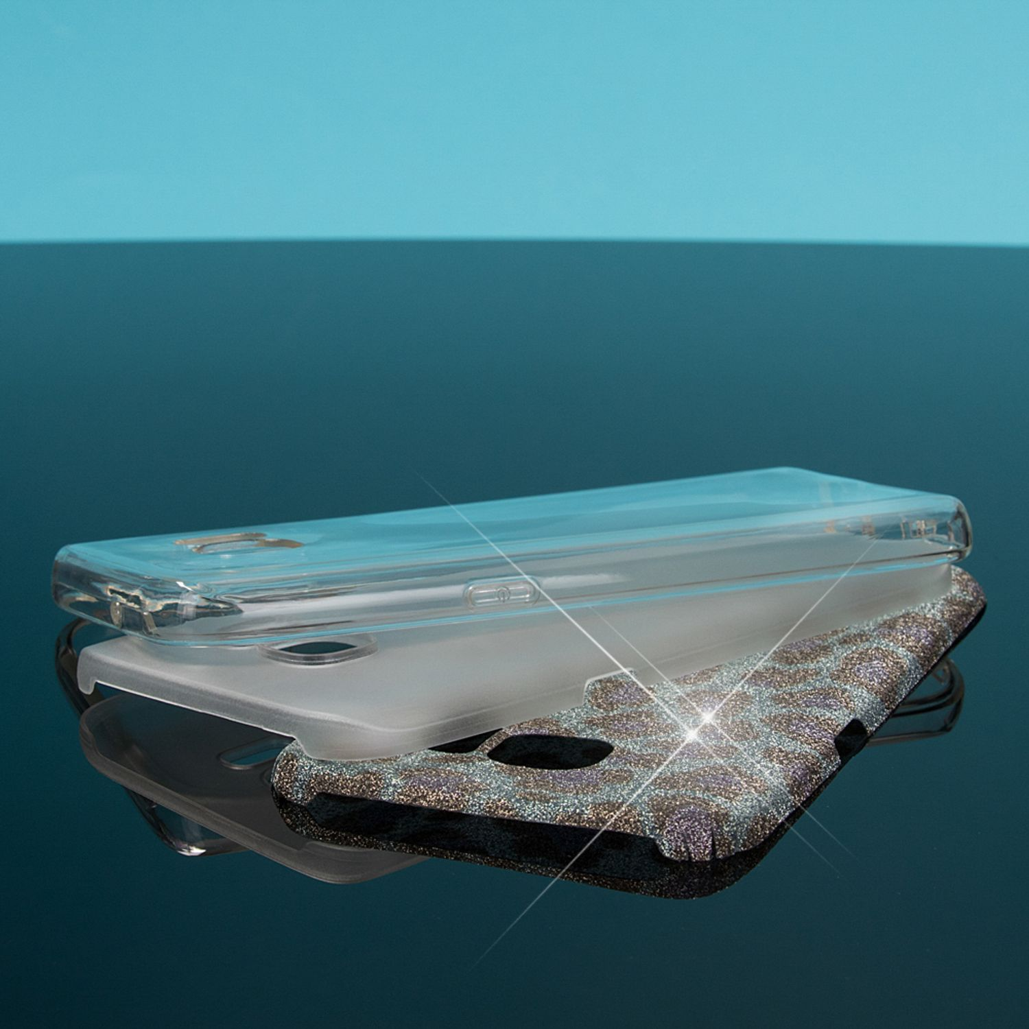 Transparente und Glitzer-Handyhüllen auf reflektierender Oberfläche mit blauem Hintergrund.