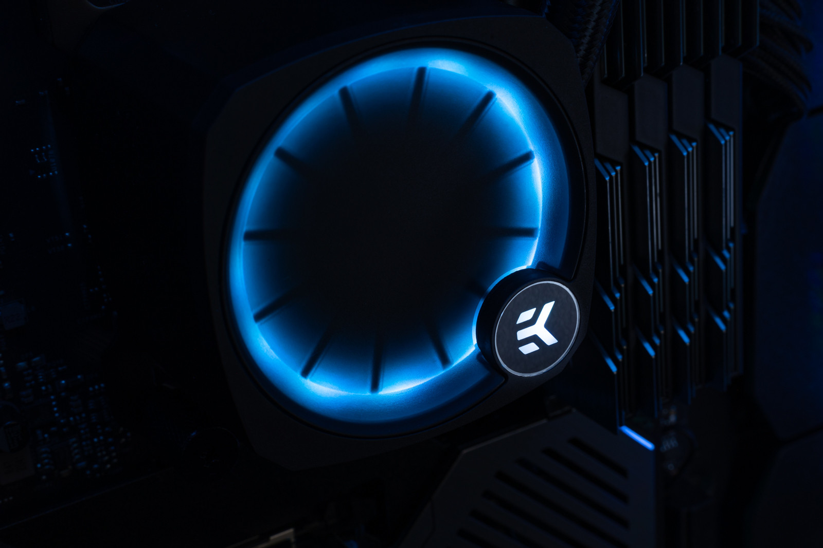 Primo piano di una ventola del computer con luci blu. La ventola ha un design circolare. Sfondo nero.