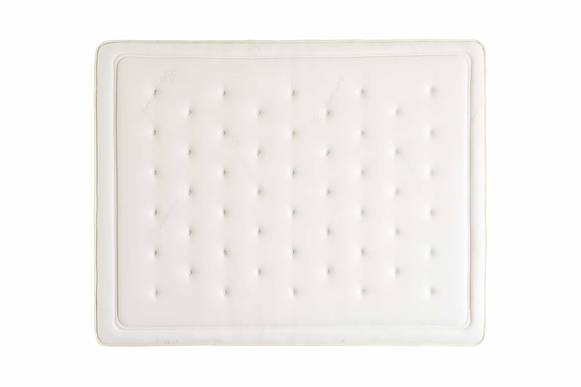 Vista superior de un colchón blanco con superficie capitoné y borde decorativo.