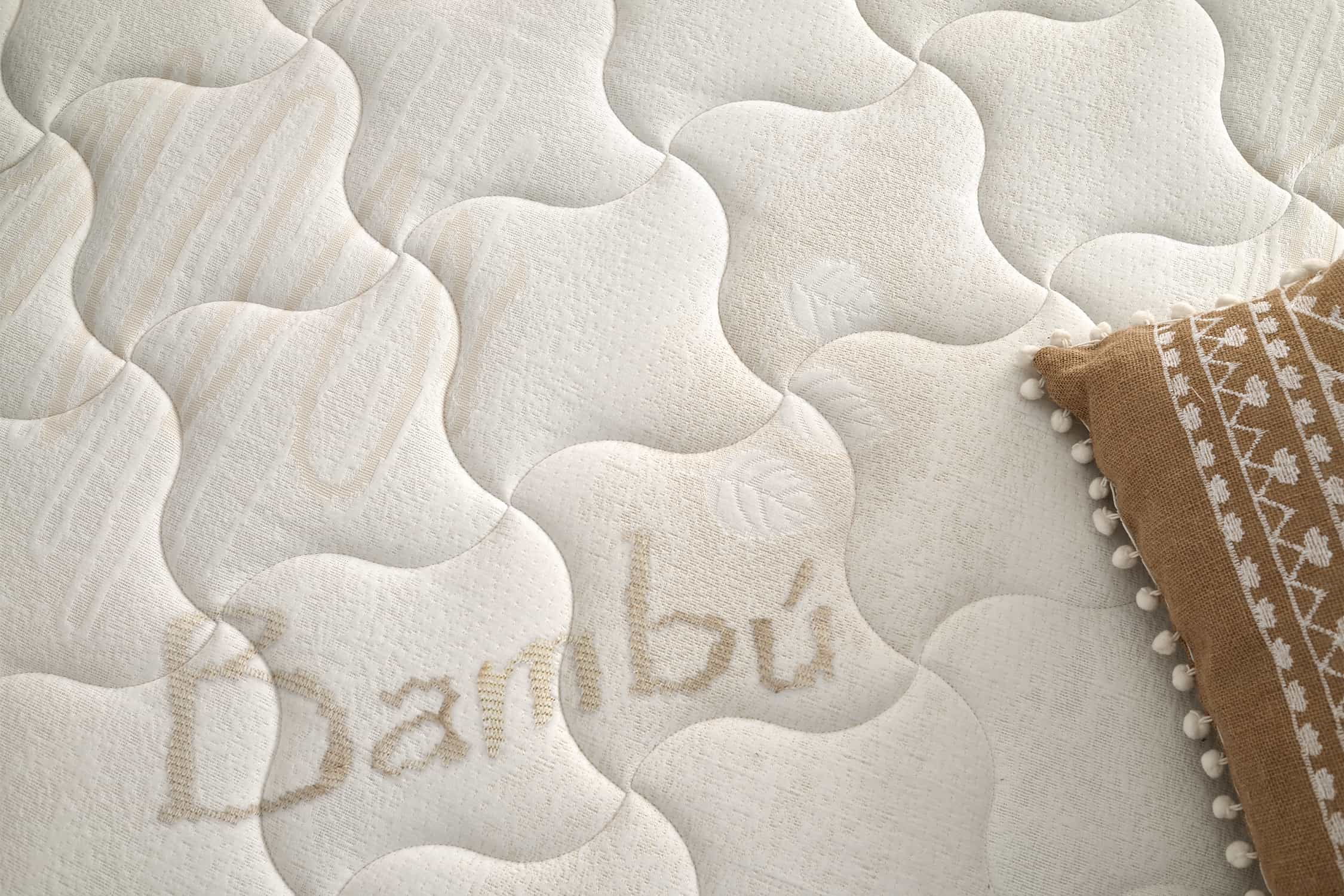 Primer plano de un colchón con superficie acolchada y la palabra 'Bambú' bordada.