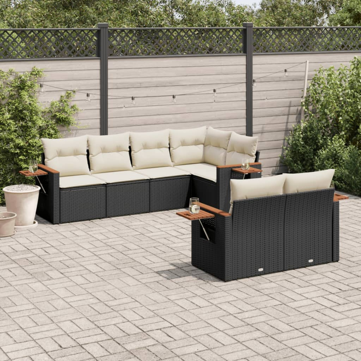Terrassenmöbel, schwarzes Korbssofa-Set mit beigefarbenen Kissen und Holzarmlehnen, auf einer Backsteinterrasse.