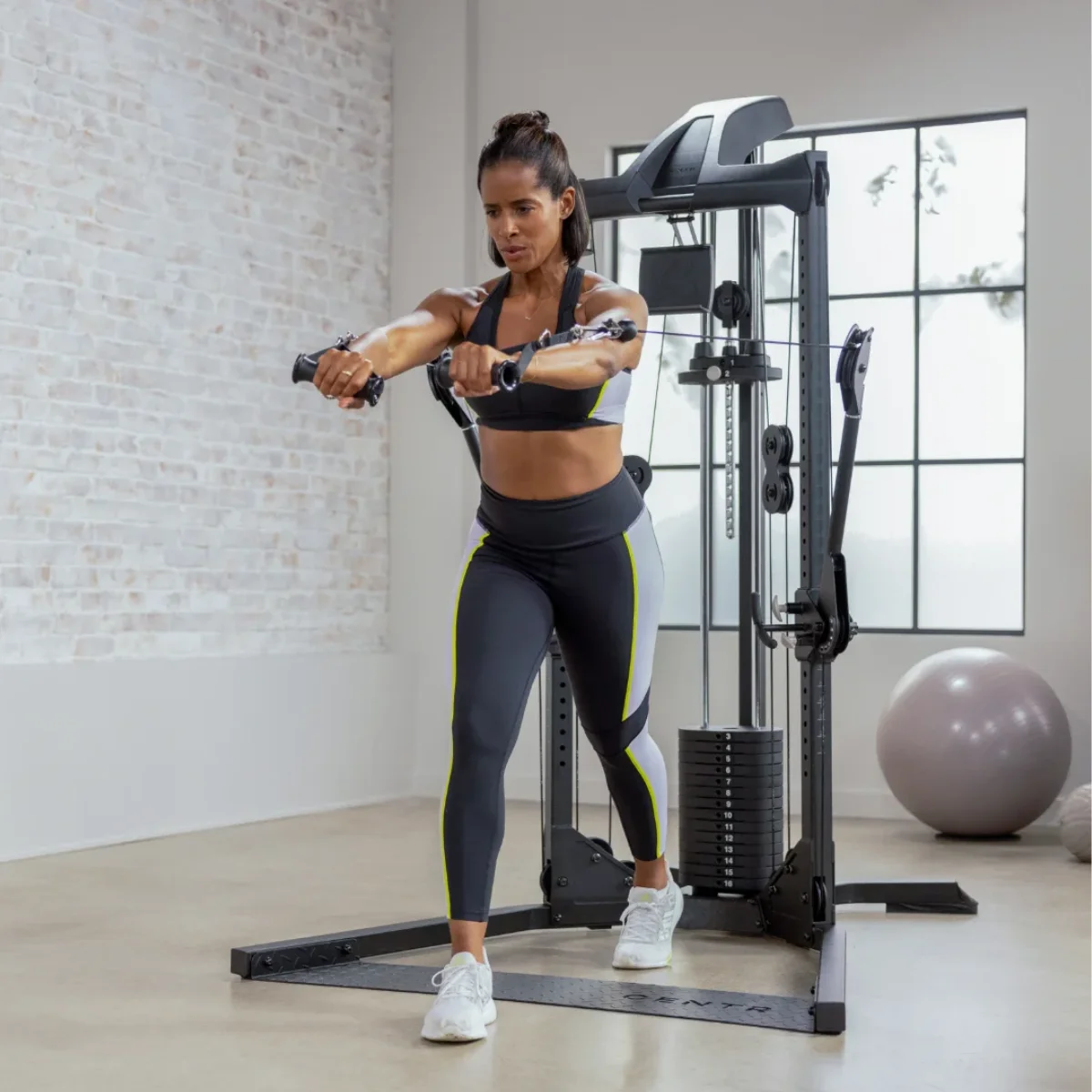 Frau trainiert mit einer Kabelzugmaschine im Fitnessstudio.