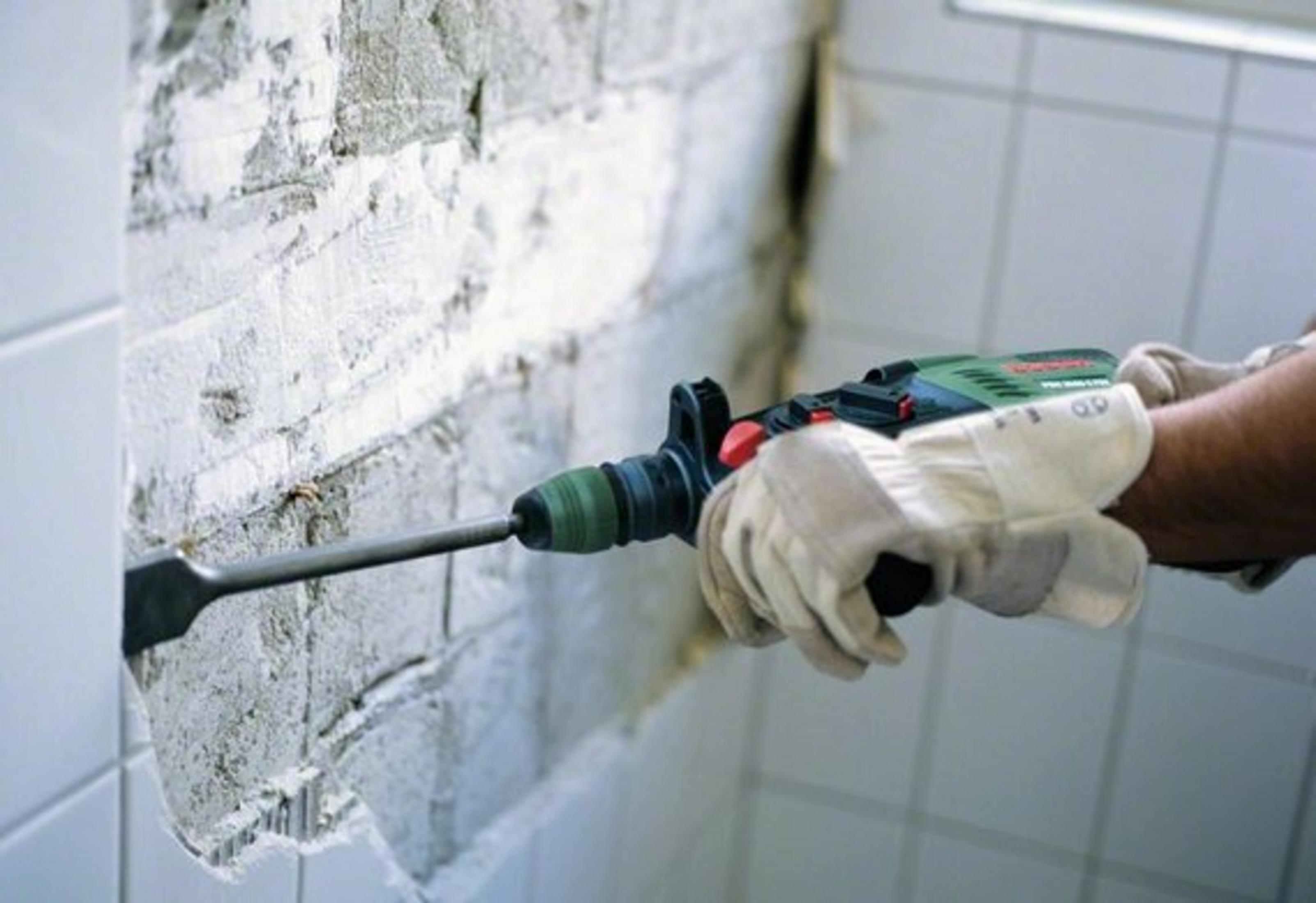 Persona usando un taladro Bosch para taladrar una pared de ladrillo.