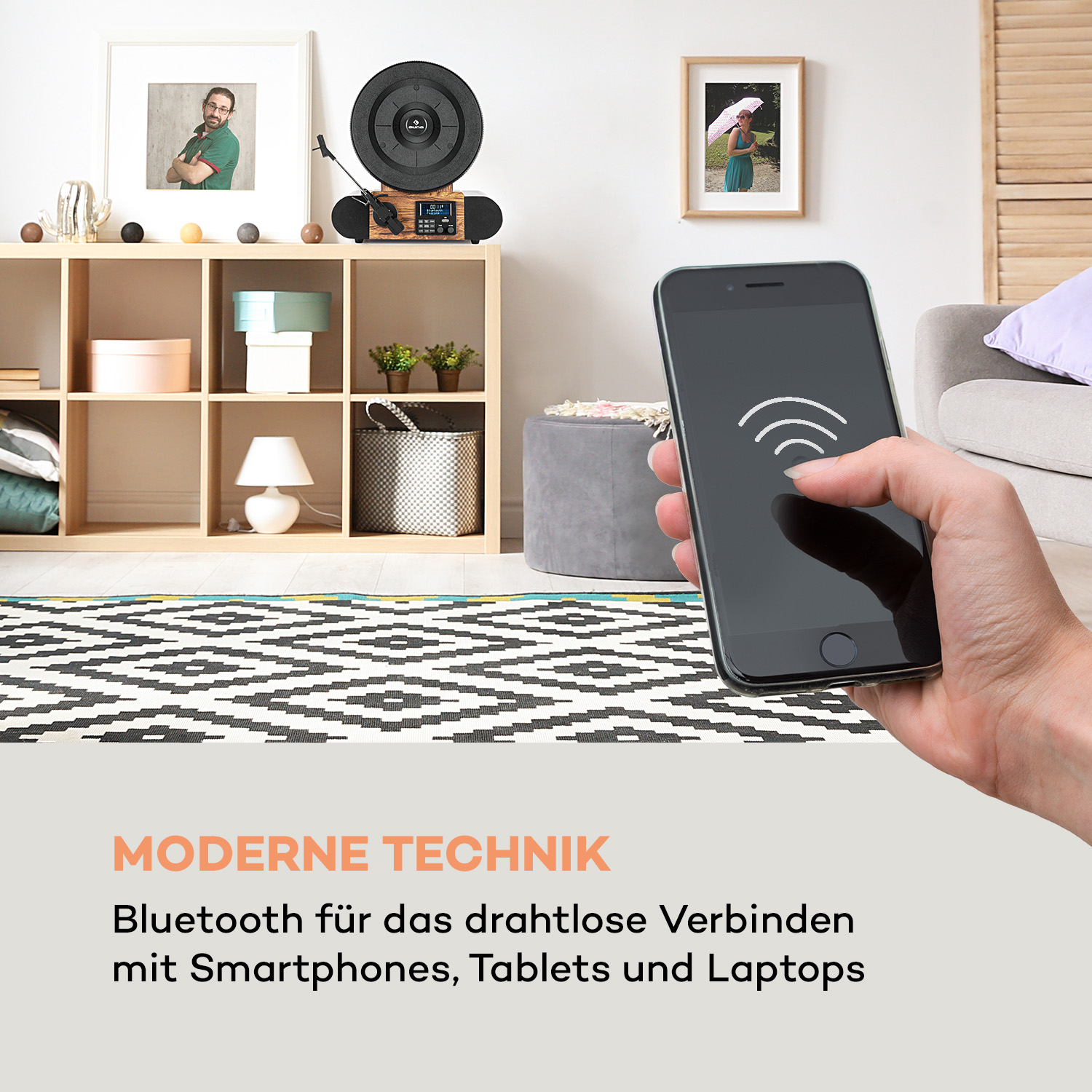 Eine Person hält ein Telefon, einen Plattenspieler und Heimdekoration im Hintergrund.