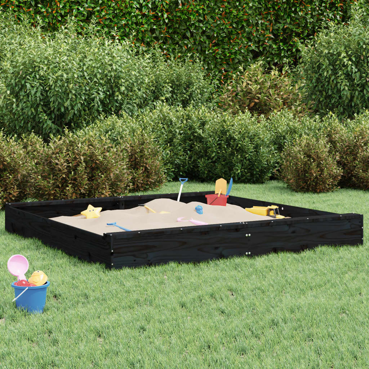 Ein Sandkasten mit Sand und Spielzeug, umgeben von grünem Gras.