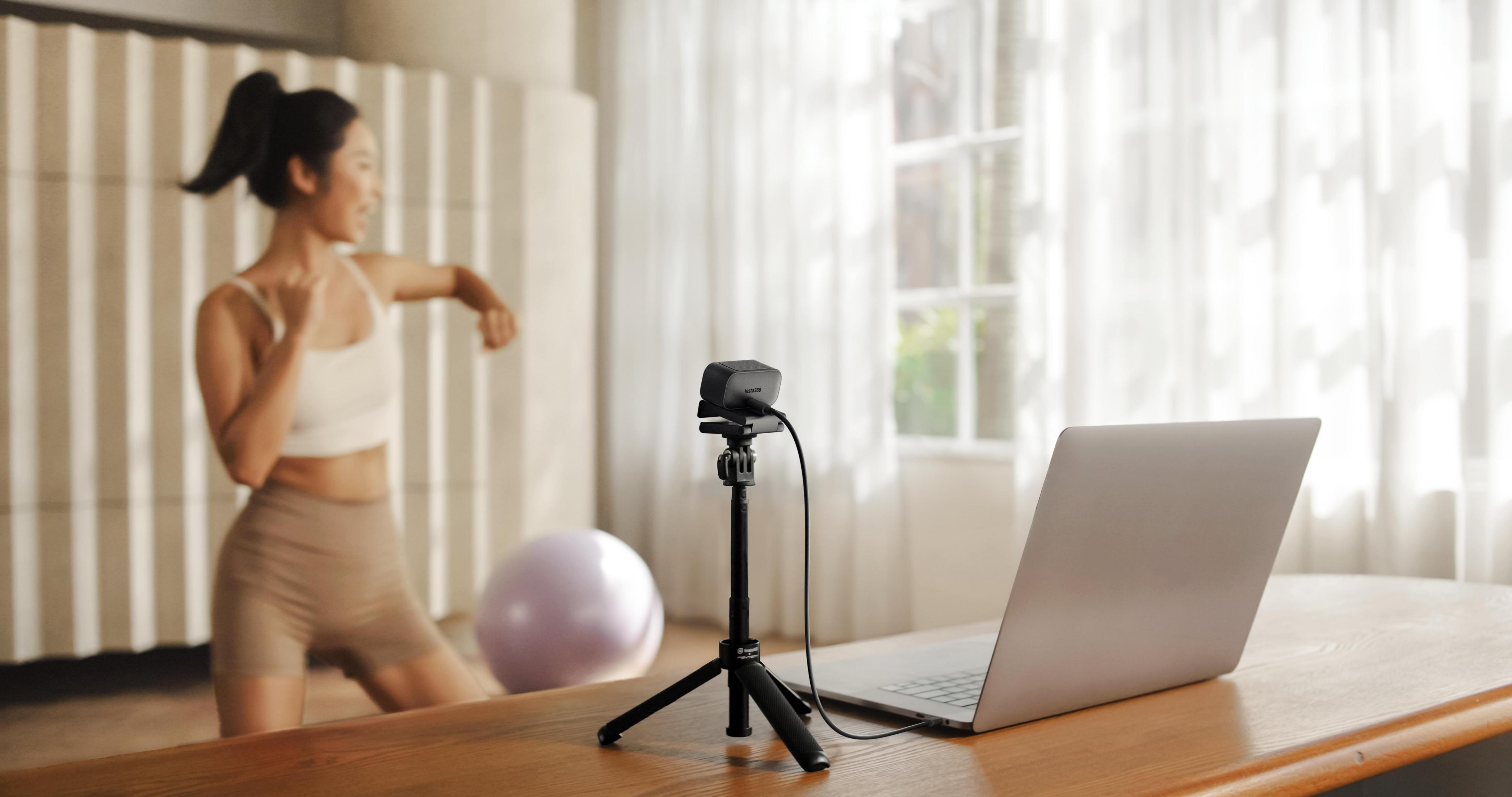 Kobieta ćwiczy przed laptopem z kamerą internetową.