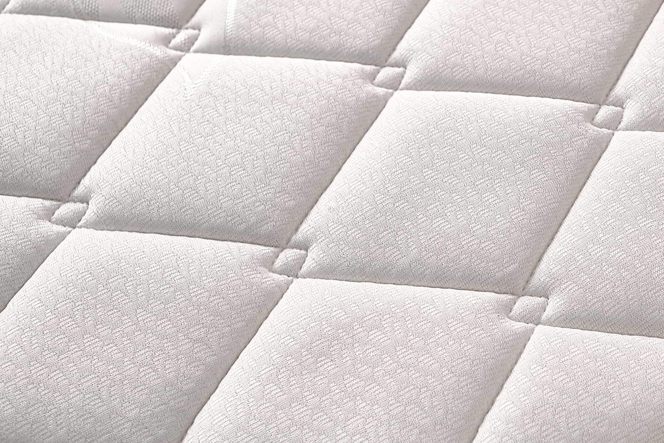 Primer plano de la superficie de un colchón blanco, diseño acolchado con cuadrados cosidos.