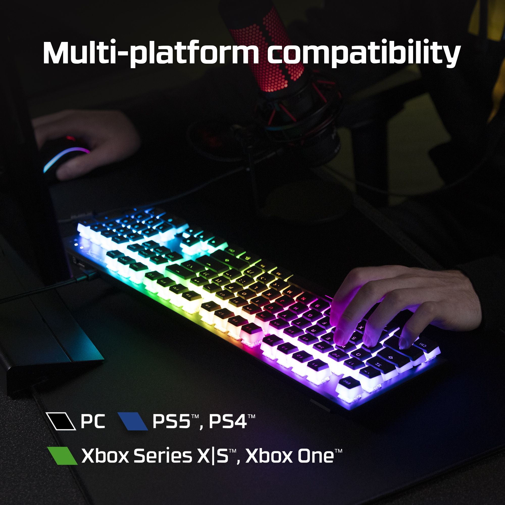 Podświetlana klawiatura z tęczowymi światłami. Ręce na klawiaturze i myszy. Pokazano zgodność z PC, PS5, PS4 i Xbox.
