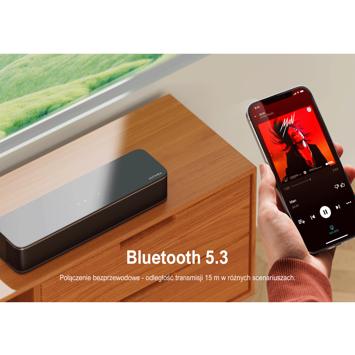 Soundbar na szafce. Osoba trzyma telefon z aplikacją muzyczną na ekranie.