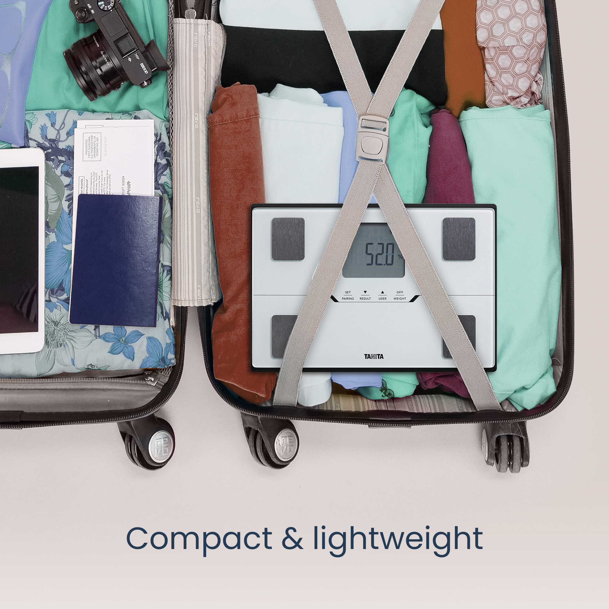 Open koffer met kleding, een weegschaal, paspoort en camera; tekst 'Compact & licht'.