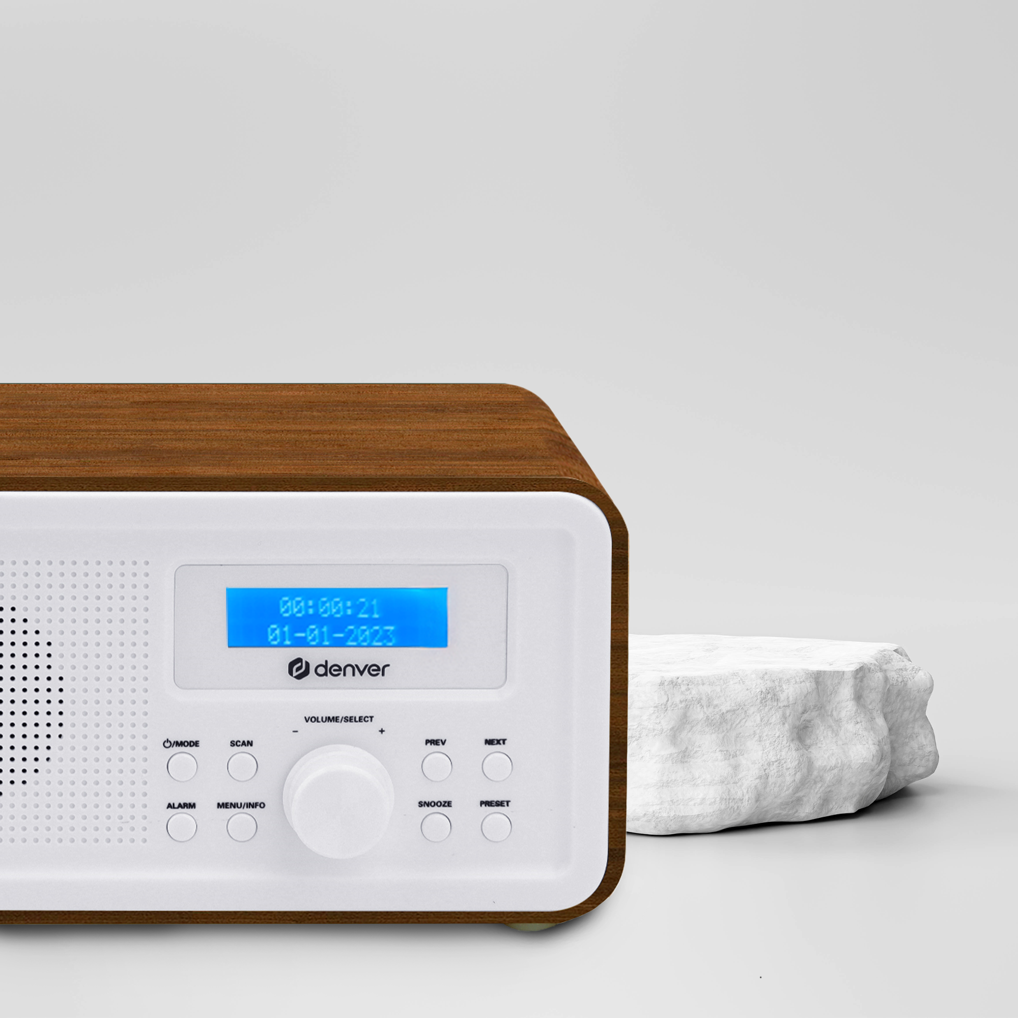 Radio mit blauem Display, Holzoptik, weißer Front. Heller Hintergrund und weißer Felsen. Denver Logo.