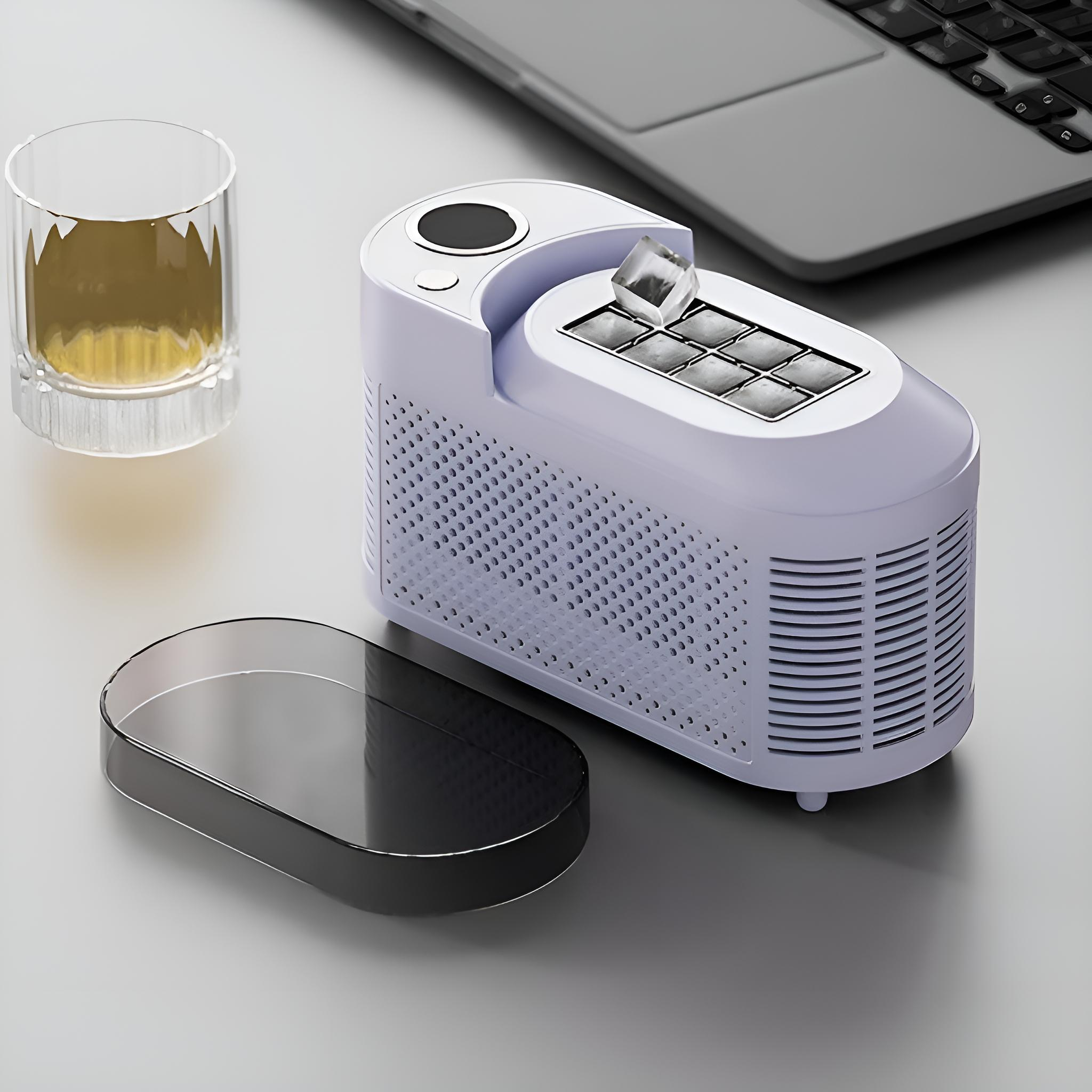 Weißer Eisbereiter mit Eiswürfeln, Glas mit Getränk und Laptop auf grauer Oberfläche. Schwarzer Deckel.