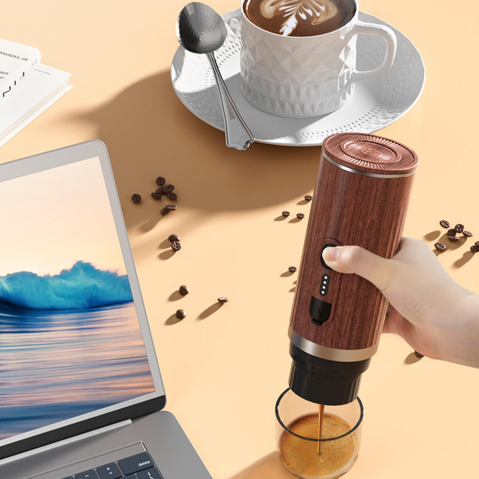 Hand gießt Kaffee ein. Espressomaschine, Kaffeetasse und Bohnen auf Tisch mit Laptop.
