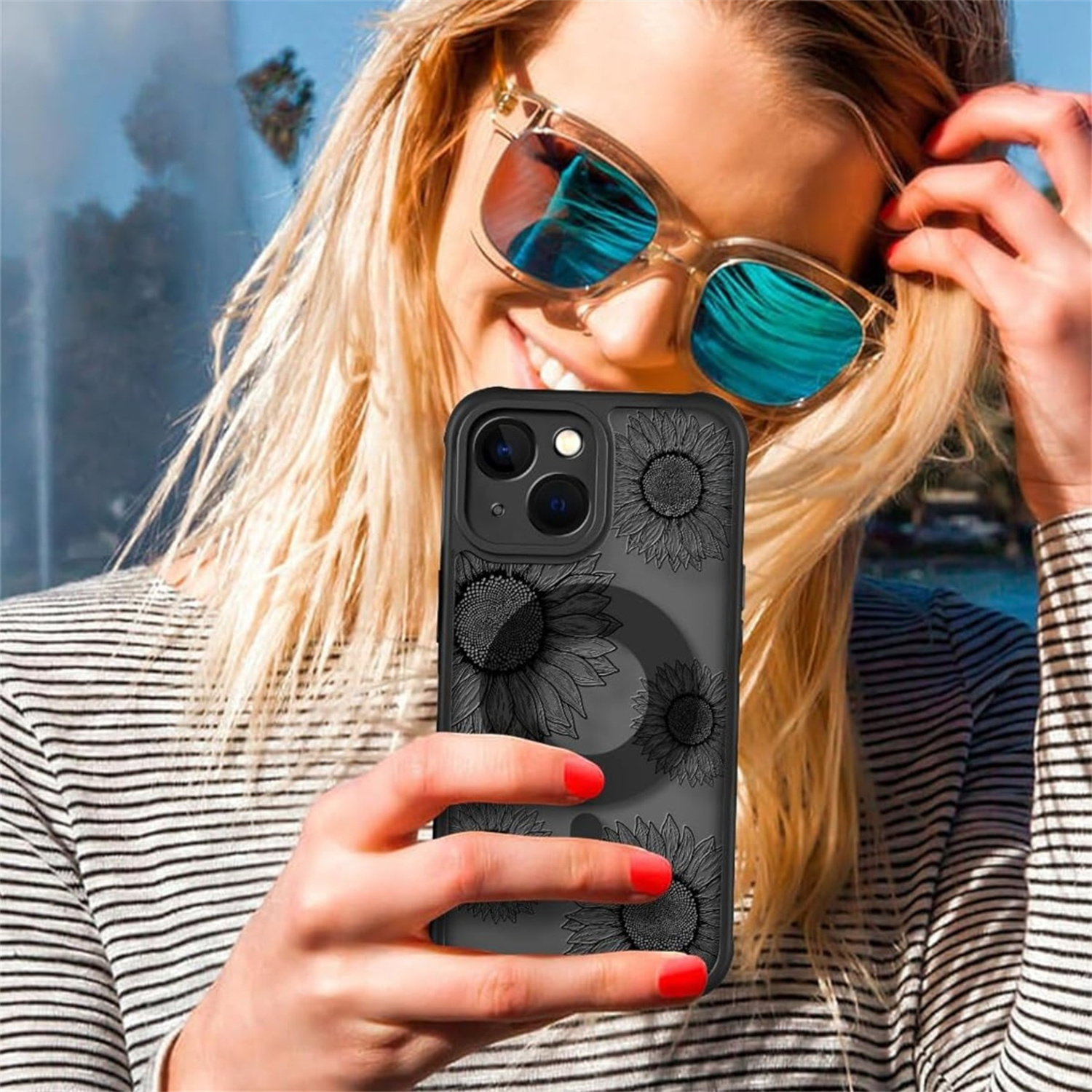 Frau hält Telefon mit Sonnenblumenhülle, trägt Sonnenbrille, sonniger Hintergrund.