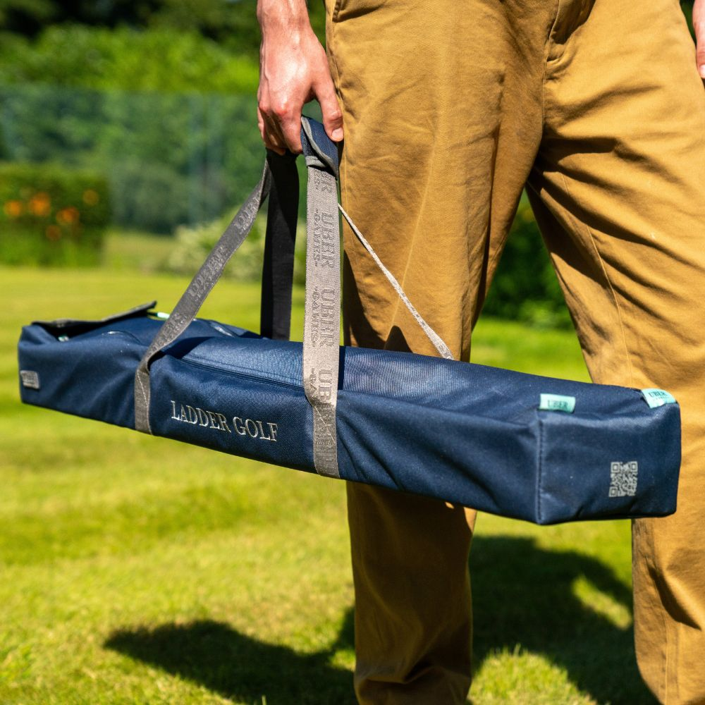 Eine Person hält eine blaue Ladder Golf Tasche auf einer grünen Grasfläche.