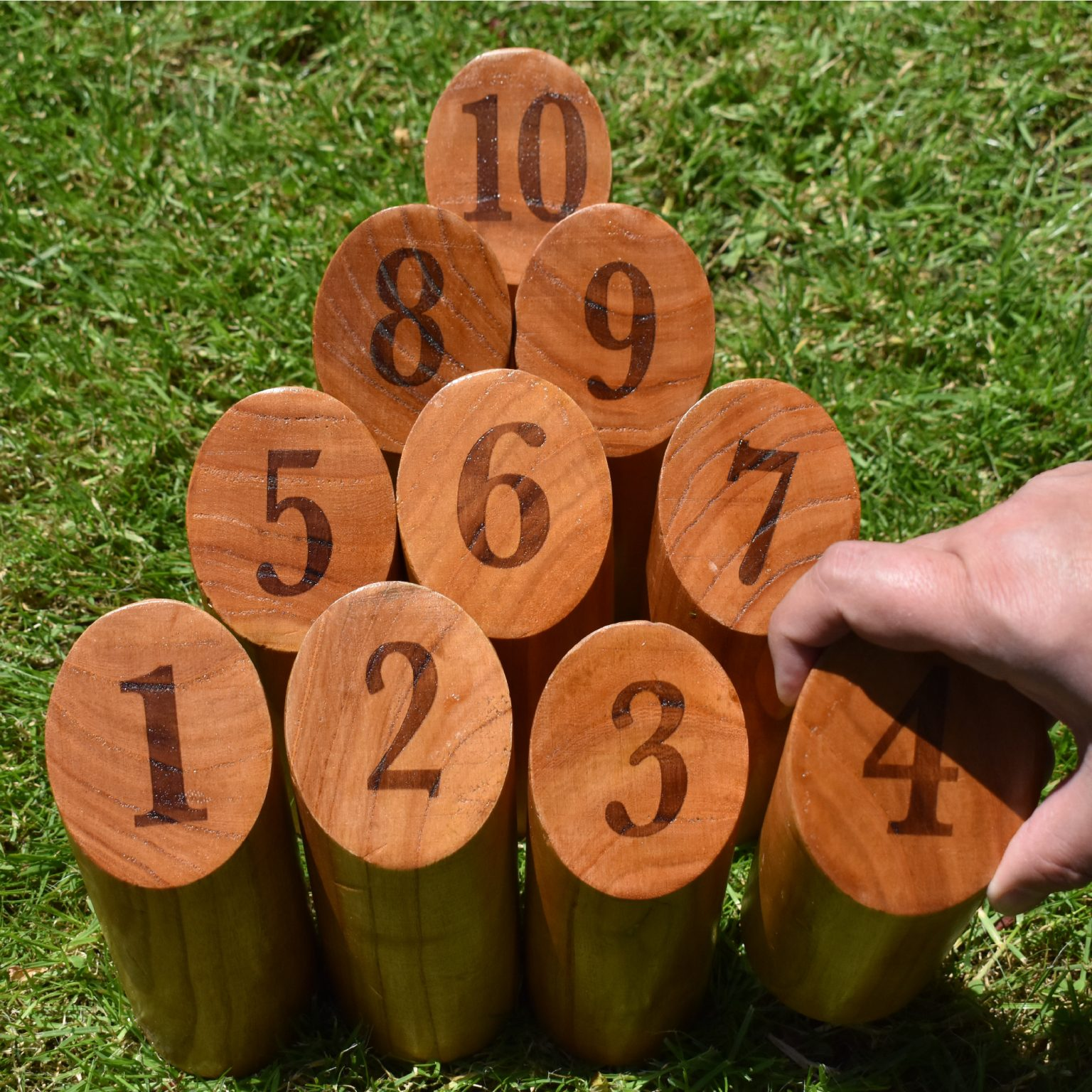 Holz-Kegel mit Zahlen von 1 bis 10, mit einer Hand, die den 4. Kegel platziert.