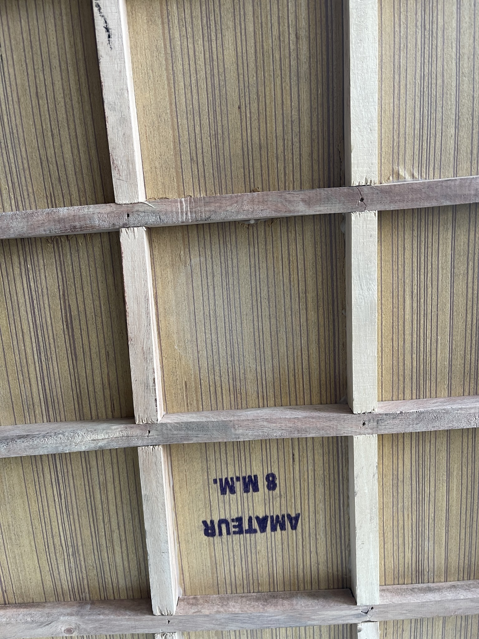 Holzkonstruktion. Beige und braune Paneele mit vertikalen Linien. Text: AMATEUR 8 M.M.