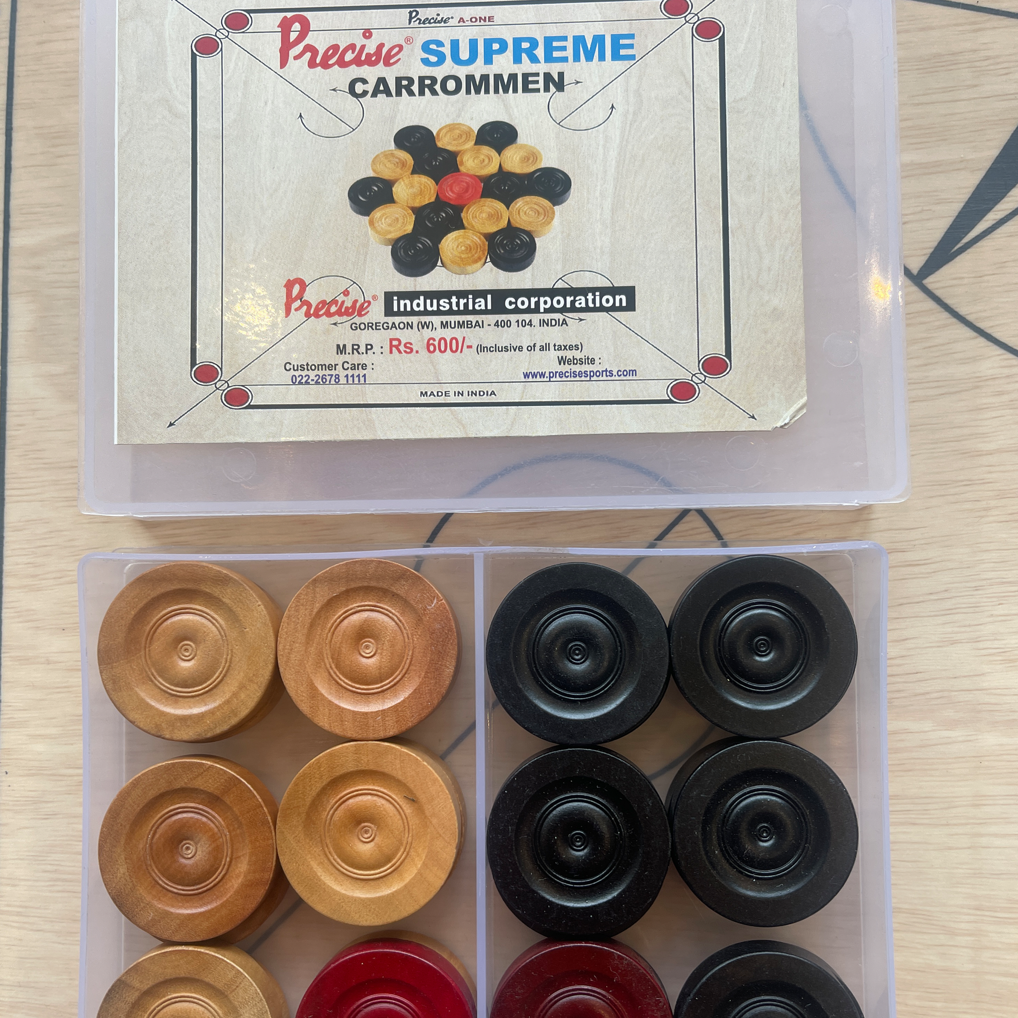 Carrom-Brettspiel-Teile. Eine Schachtel mit Carrommen und ein separater Behälter mit Carrom-Pulver und Schläger.