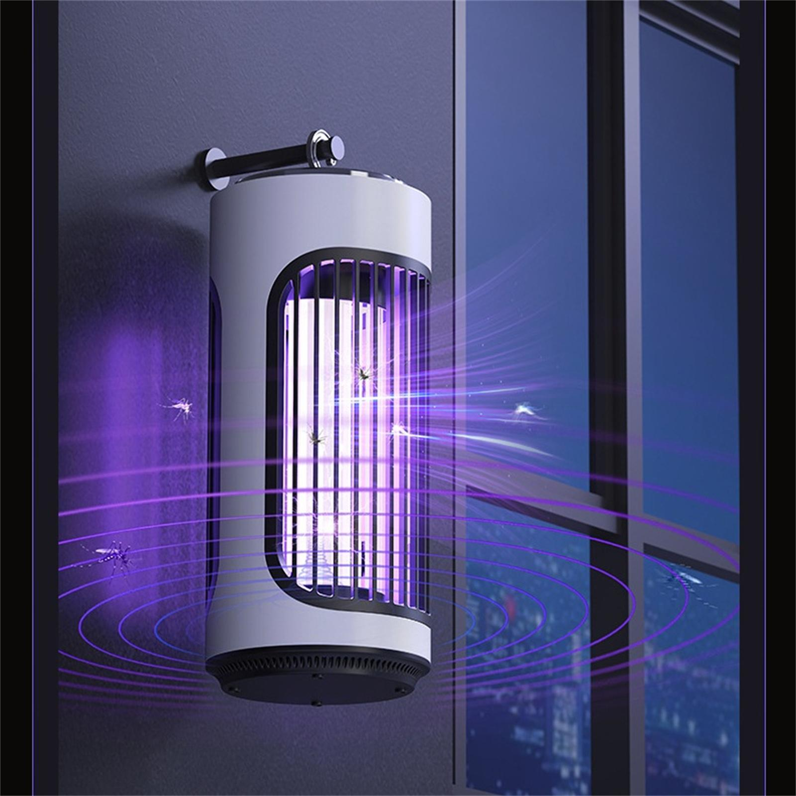 Weißer Mückenvernichter emittiert violettes Licht an einem Fenster. Fliegende Mücken um das Gerät herum. Dunkler Hintergrund.
