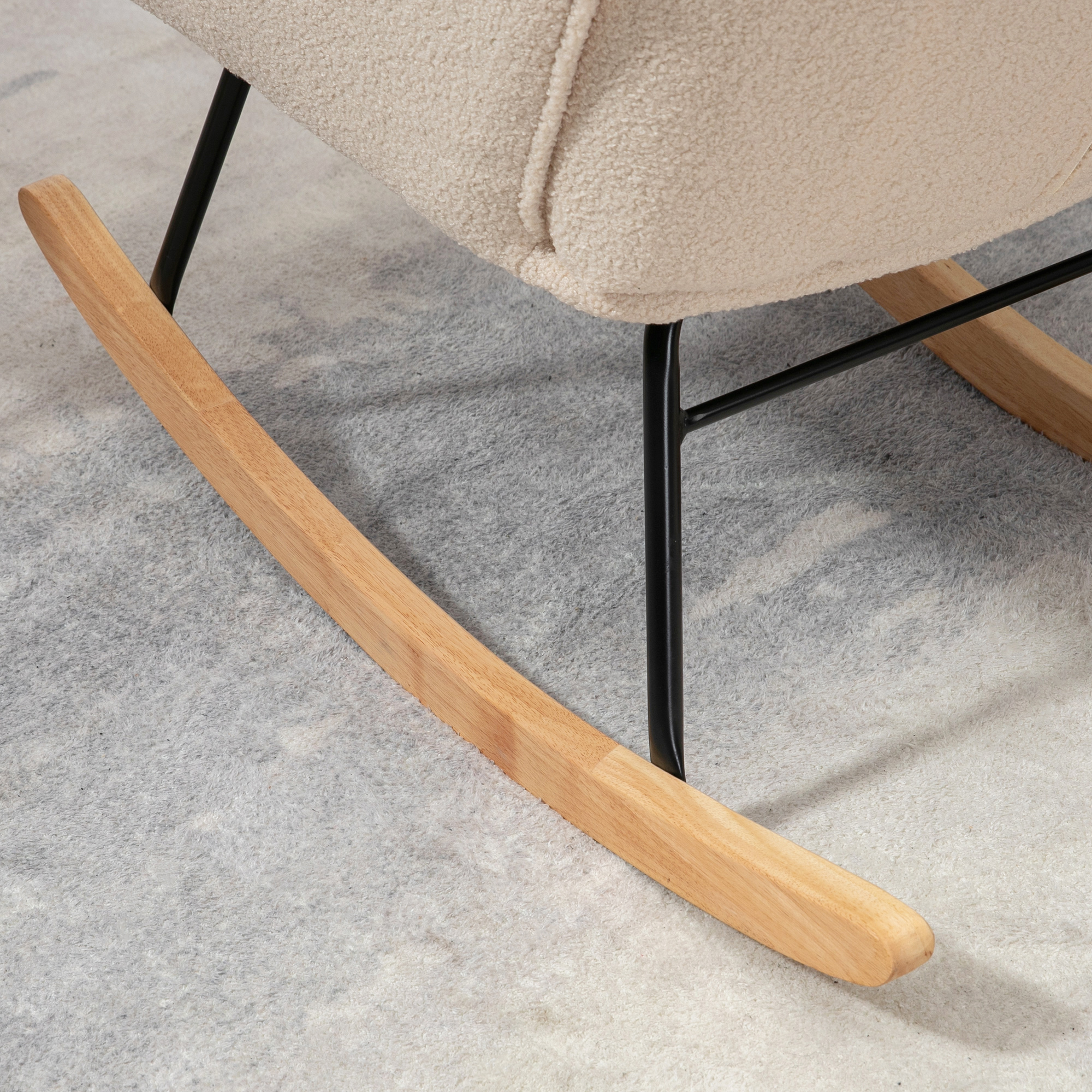 Nahaufnahme der Holzwippe eines cremefarbenen Schaukelstuhls, die auf einer grauen Oberfläche ruht.