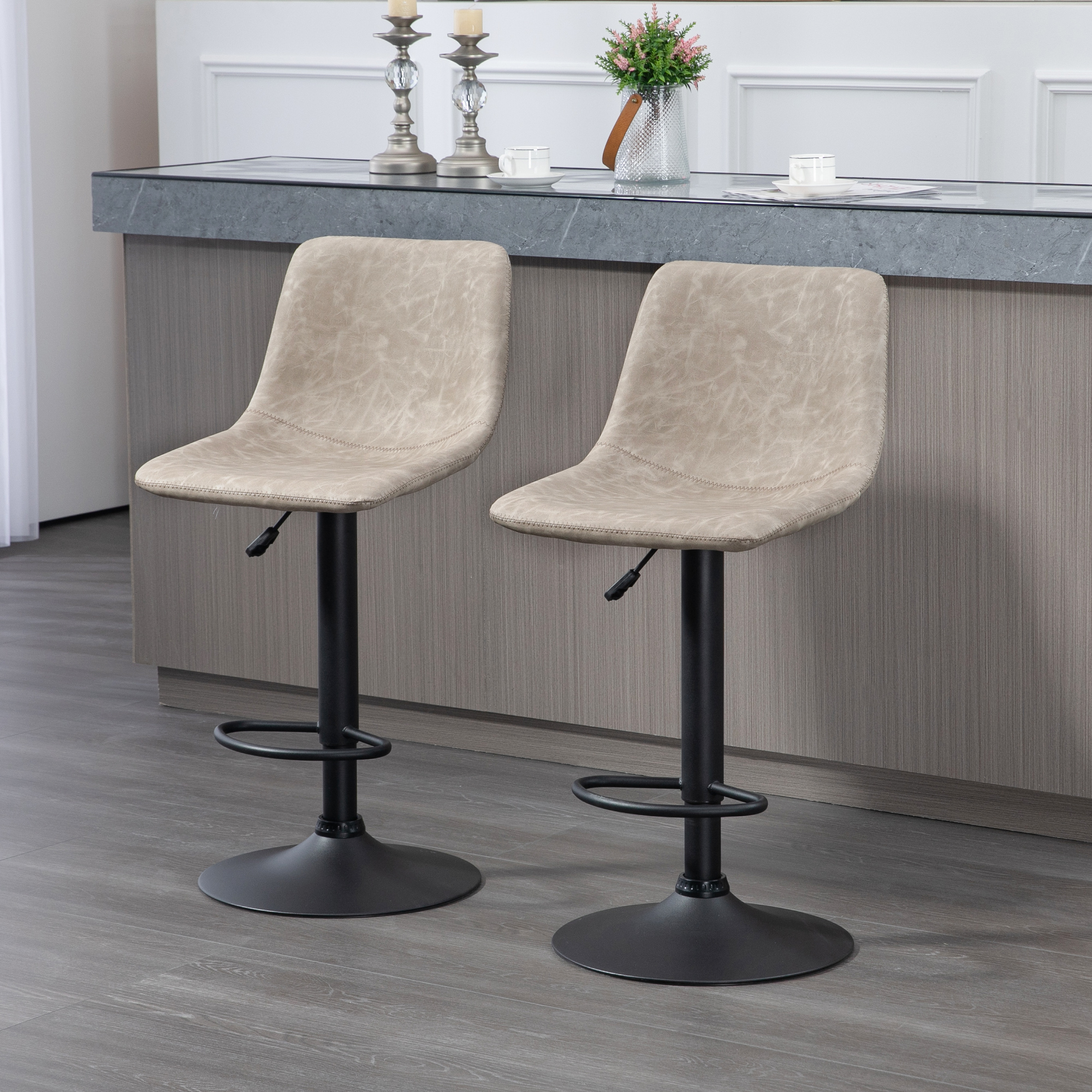 Zwei beige Barhocker mit schwarzen Basen vor einer Küchentheke. Im Hintergrund eine Arbeitsplatte und eine Vase.